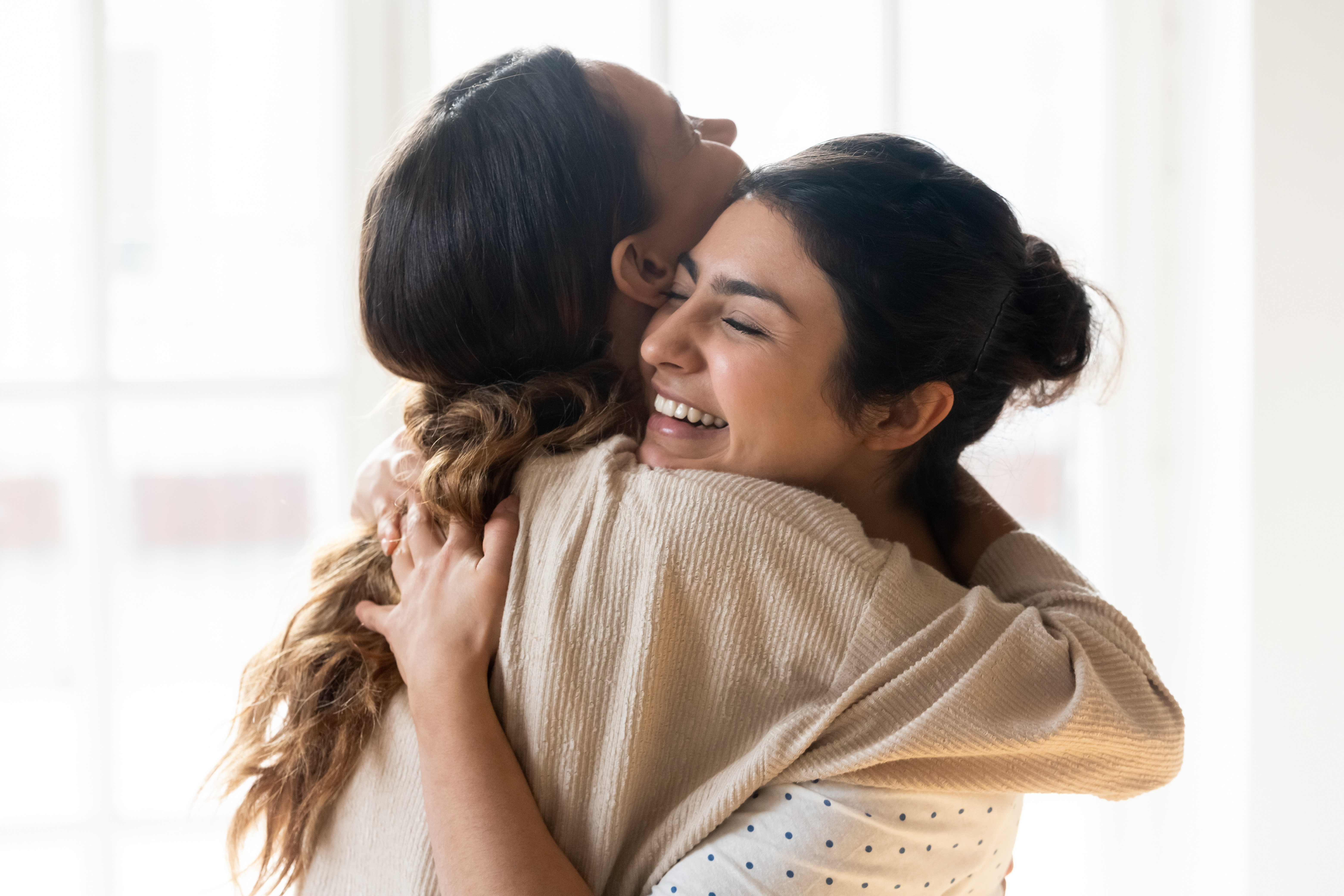 Deux femmes sourient en se serrant l'une contre l'autre | Source : Shutterstock
