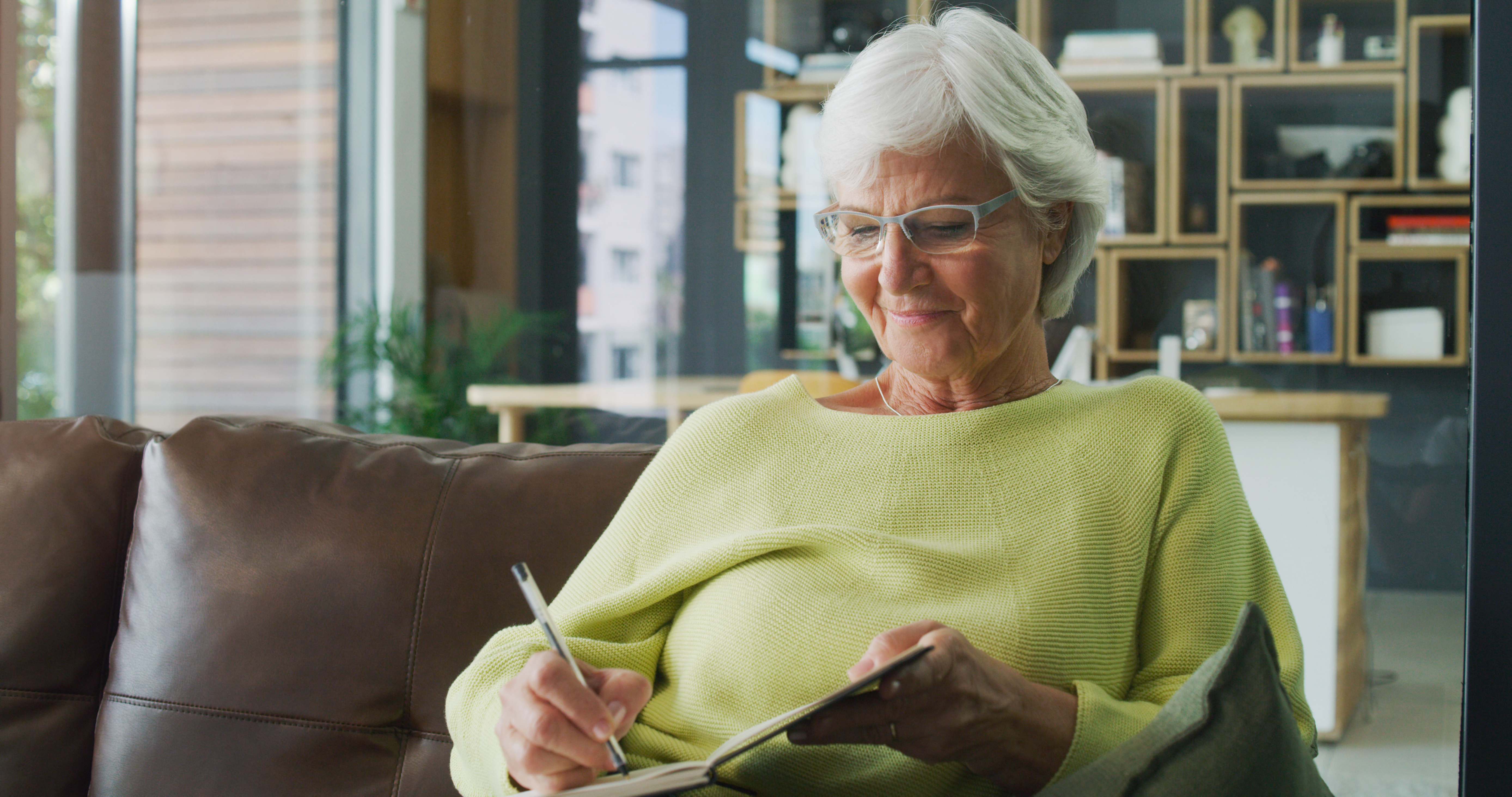 Prise de vue d'une femme âgée qui écrit dans un journal à la maison | Source : Getty Images