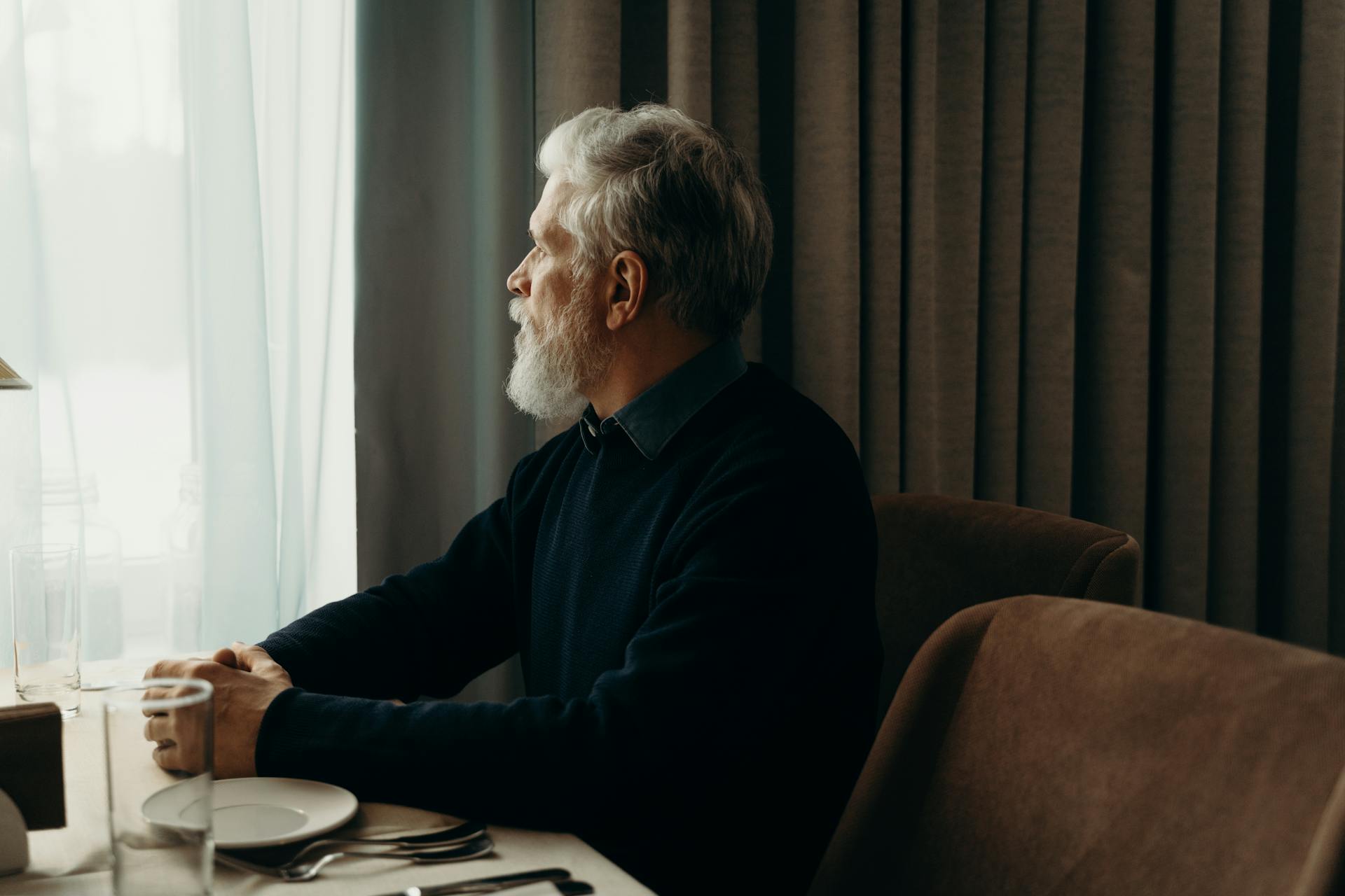 Un homme âgé qui regarde par la fenêtre tout en parlant | Source : Pexels