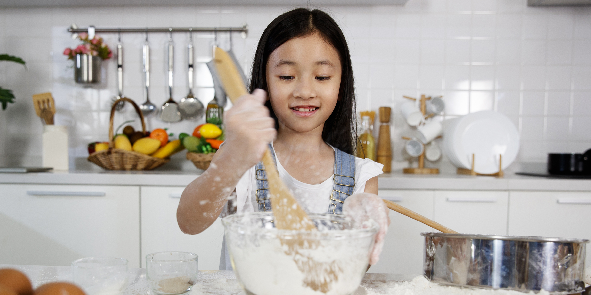 Une jeune fille mélange de la farine dans un bol | Source : Shutterstock