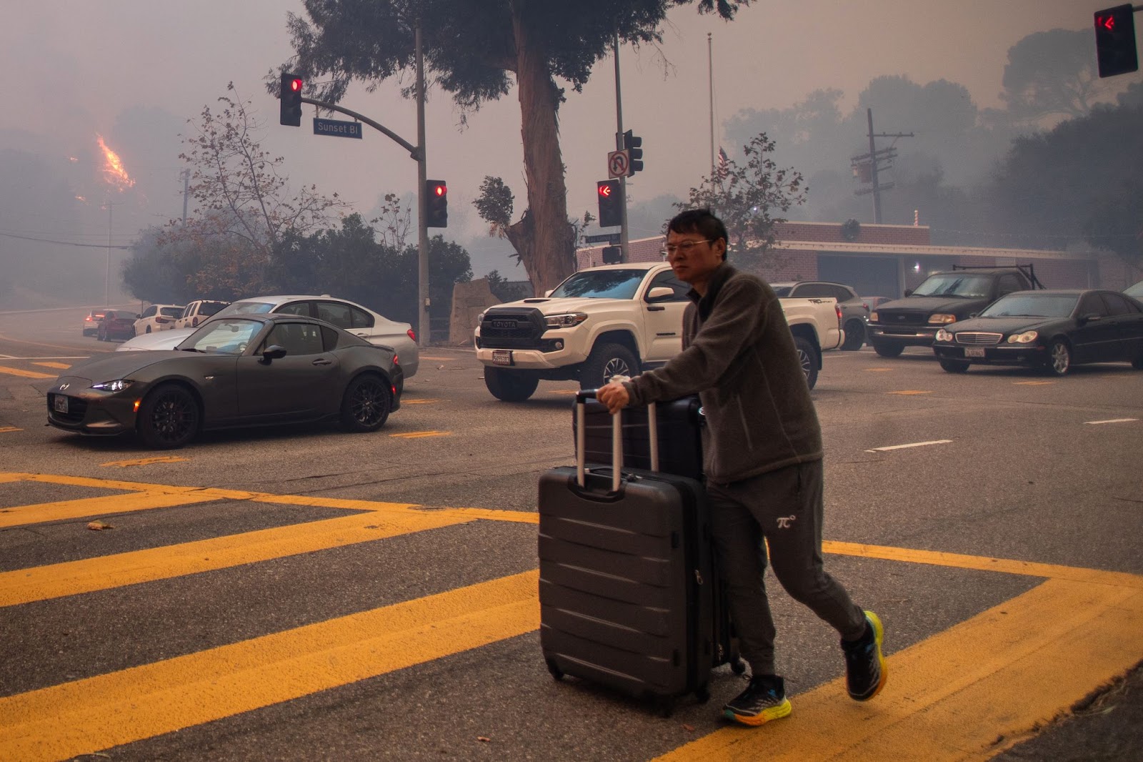 Un homme évacue le long de Sunset Boulevard alors que l'incendie brûle au milieu d'une puissante tempête de vent, le 7 janvier 2025, dans le quartier de Pacific Palisades à Los Angeles, en Californie. | Source : Getty Images