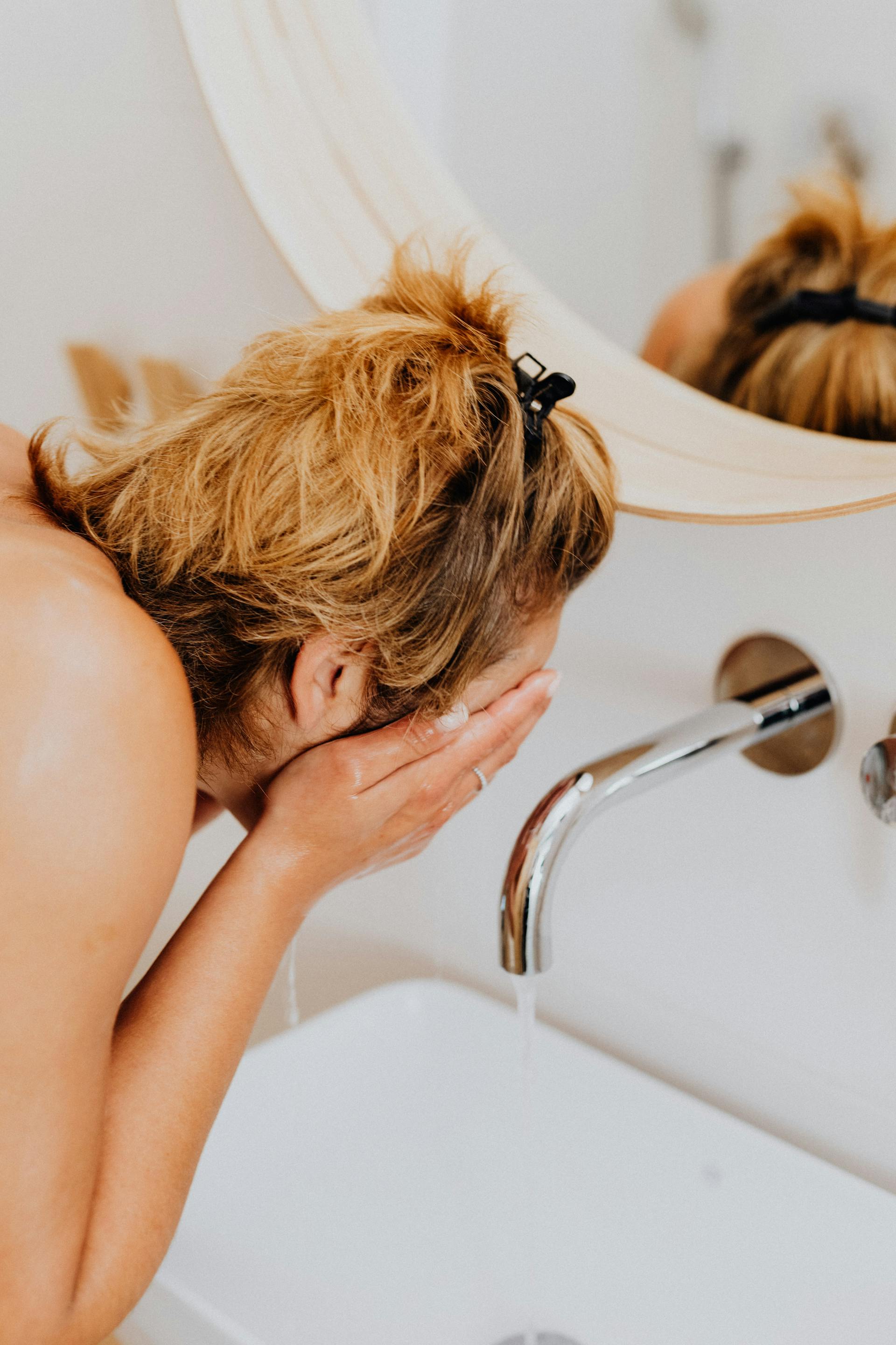 Une femme s'aspergeant le visage d'eau dans les toilettes | Source : Pexels