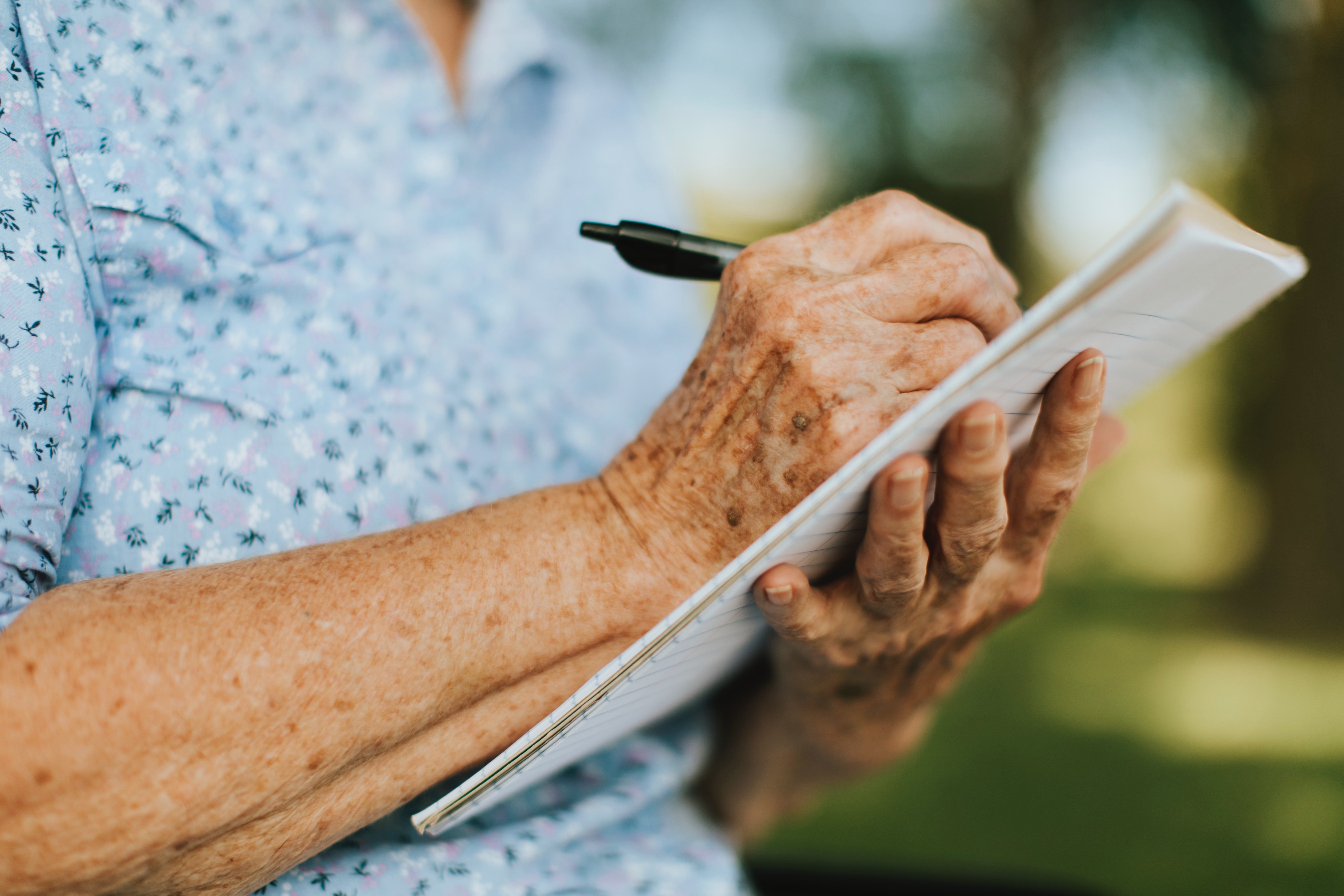 Une vieille dame écrit sur un carnet | Photo : Pexels