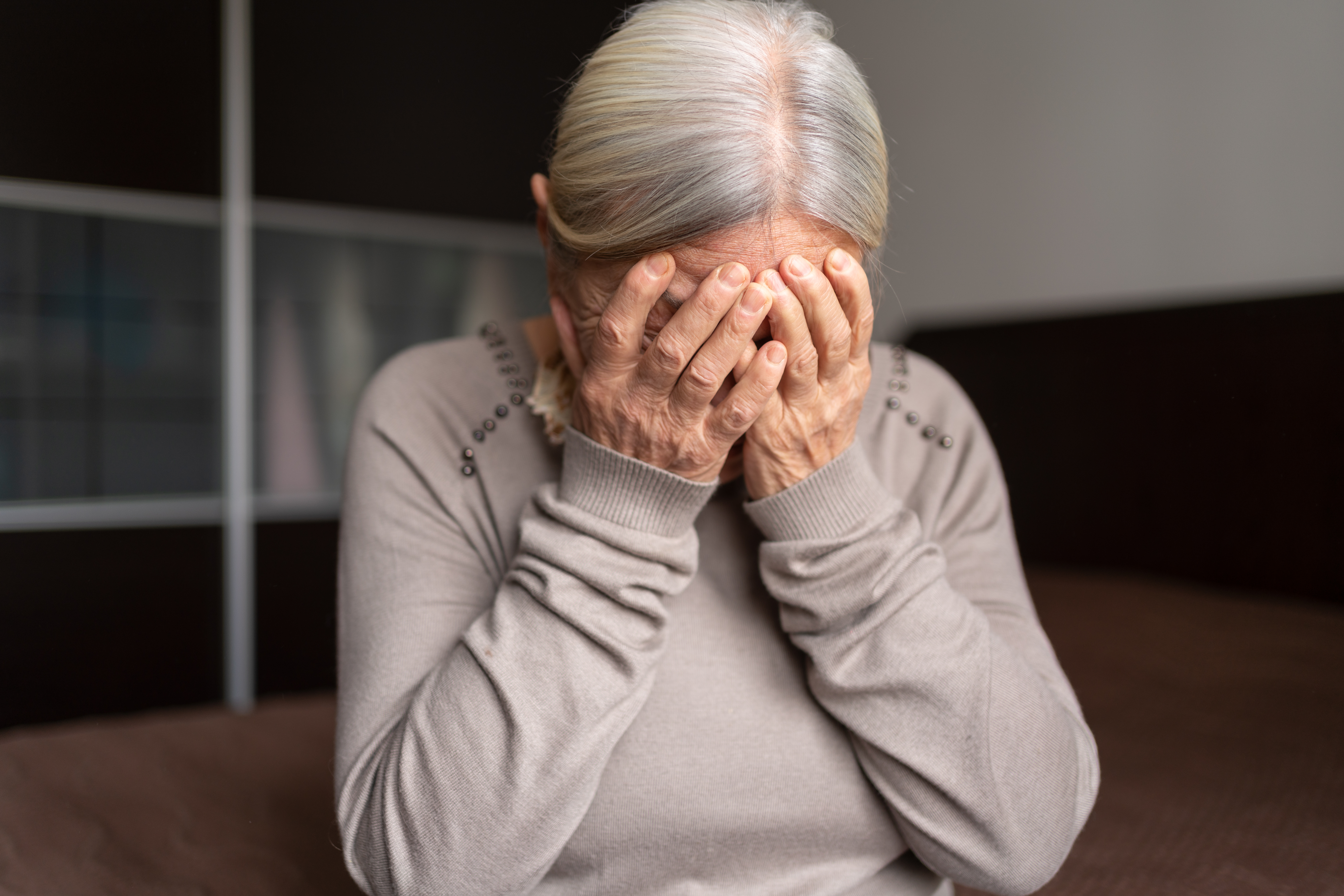 Une femme âgée seule et déprimée se couvre le visage avec ses deux mains | Source : Getty Images
