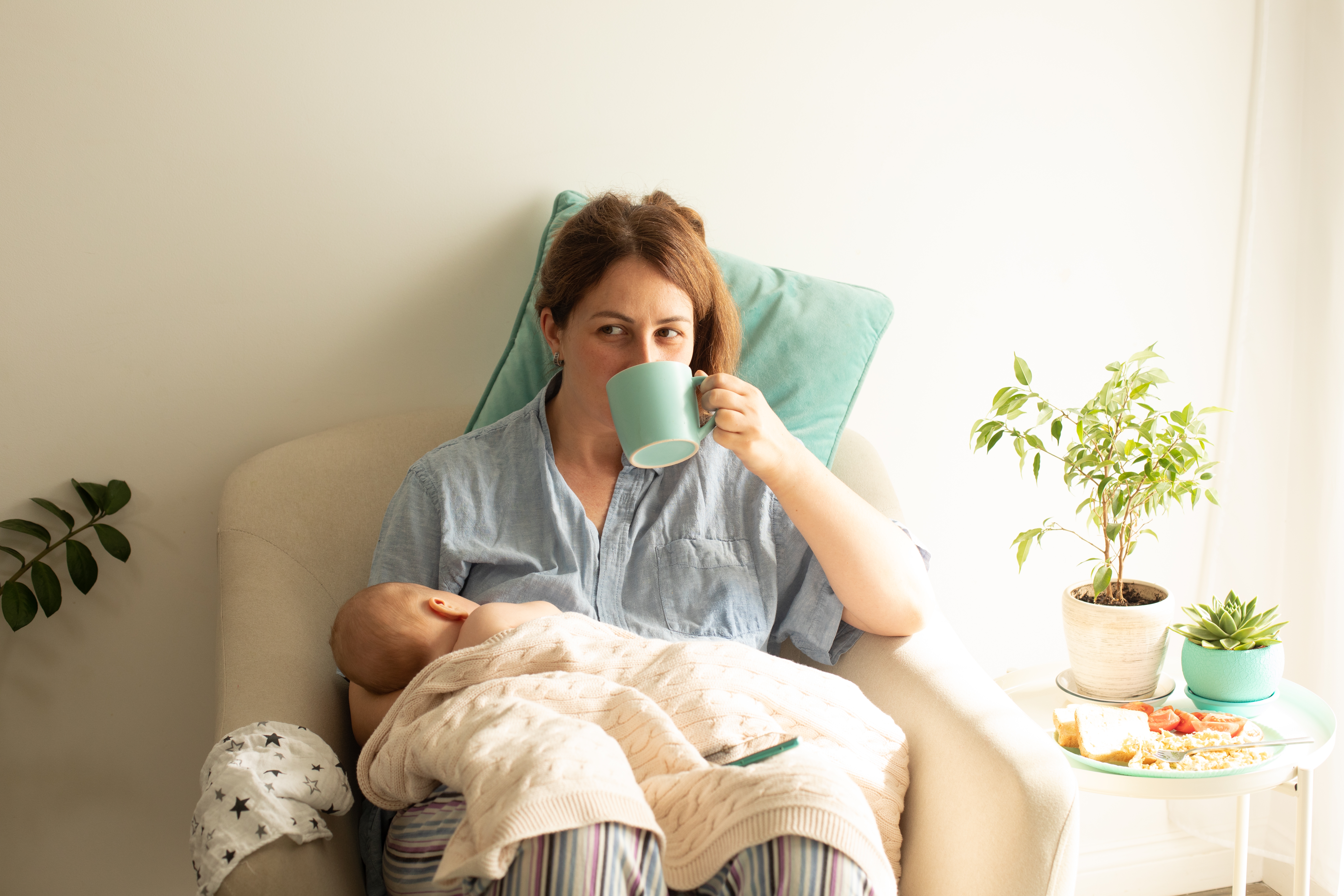 Une femme qui allaite son nouveau-né tout en buvant du thé | Source : Shutterstock