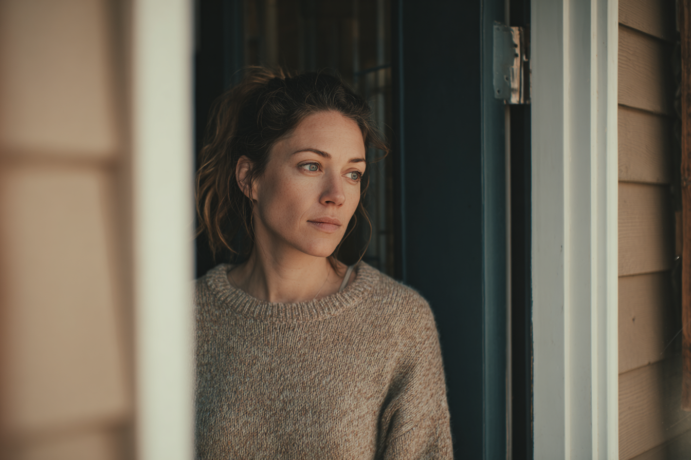Une femme debout dans l'embrasure de la porte de sa maison | Source : Midjourney