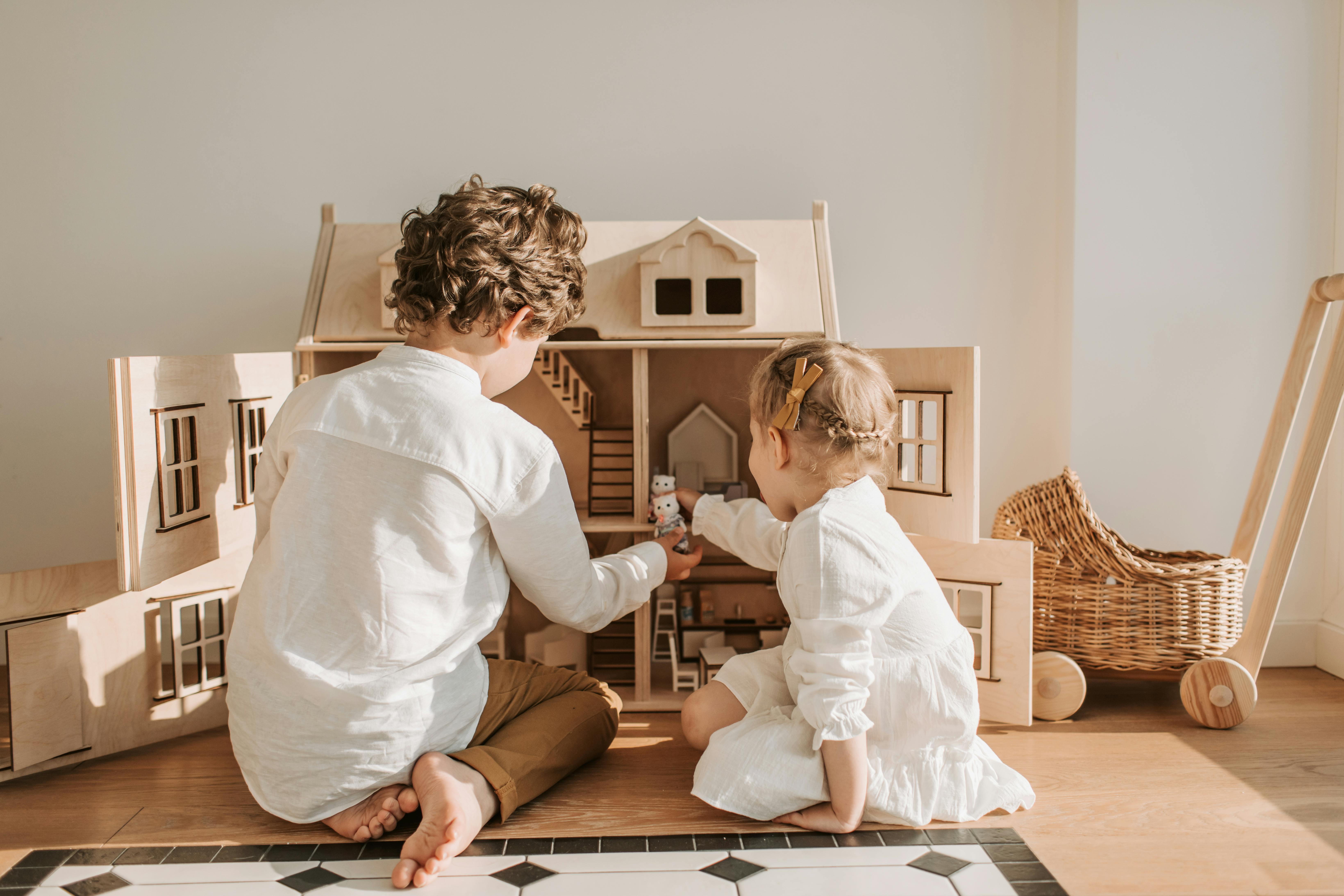 Deux enfants jouant avec une maison de poupée | Source : Pexels