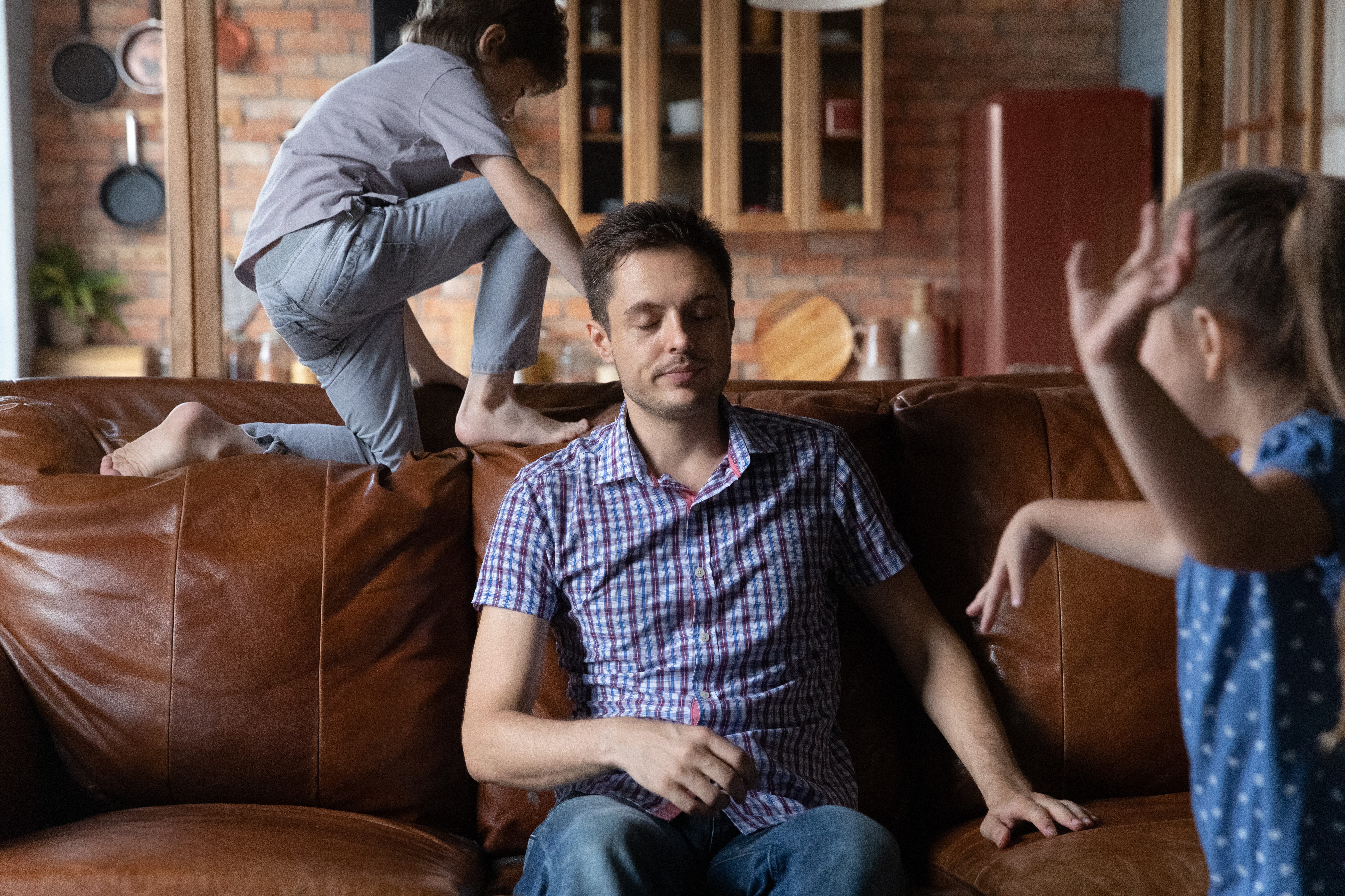 Un père se sentant épuisé à cause de ses enfants qui font du bruit | Source : Shutterstock