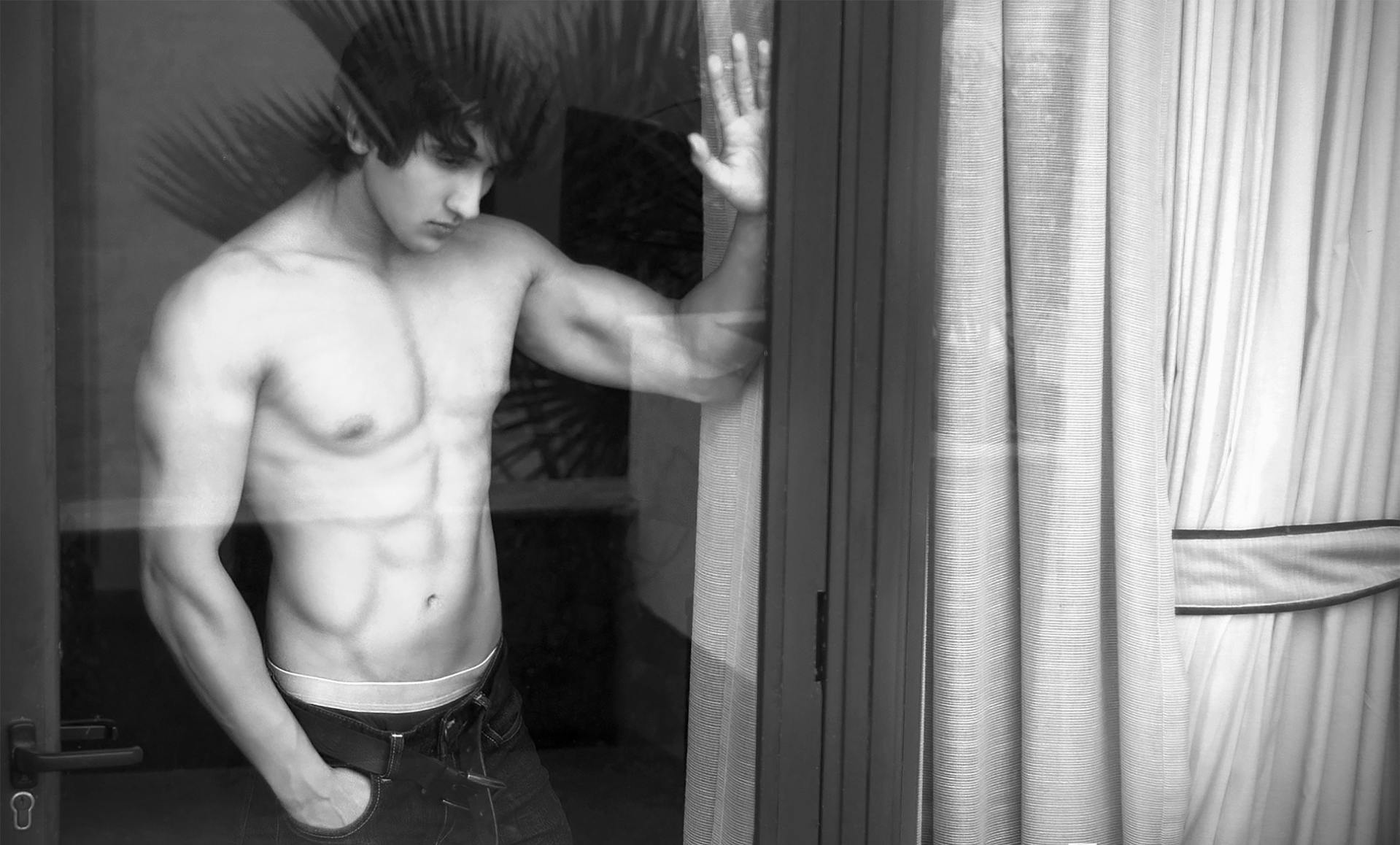 Un homme torse nu debout près d'une fenêtre | Source : Pexels