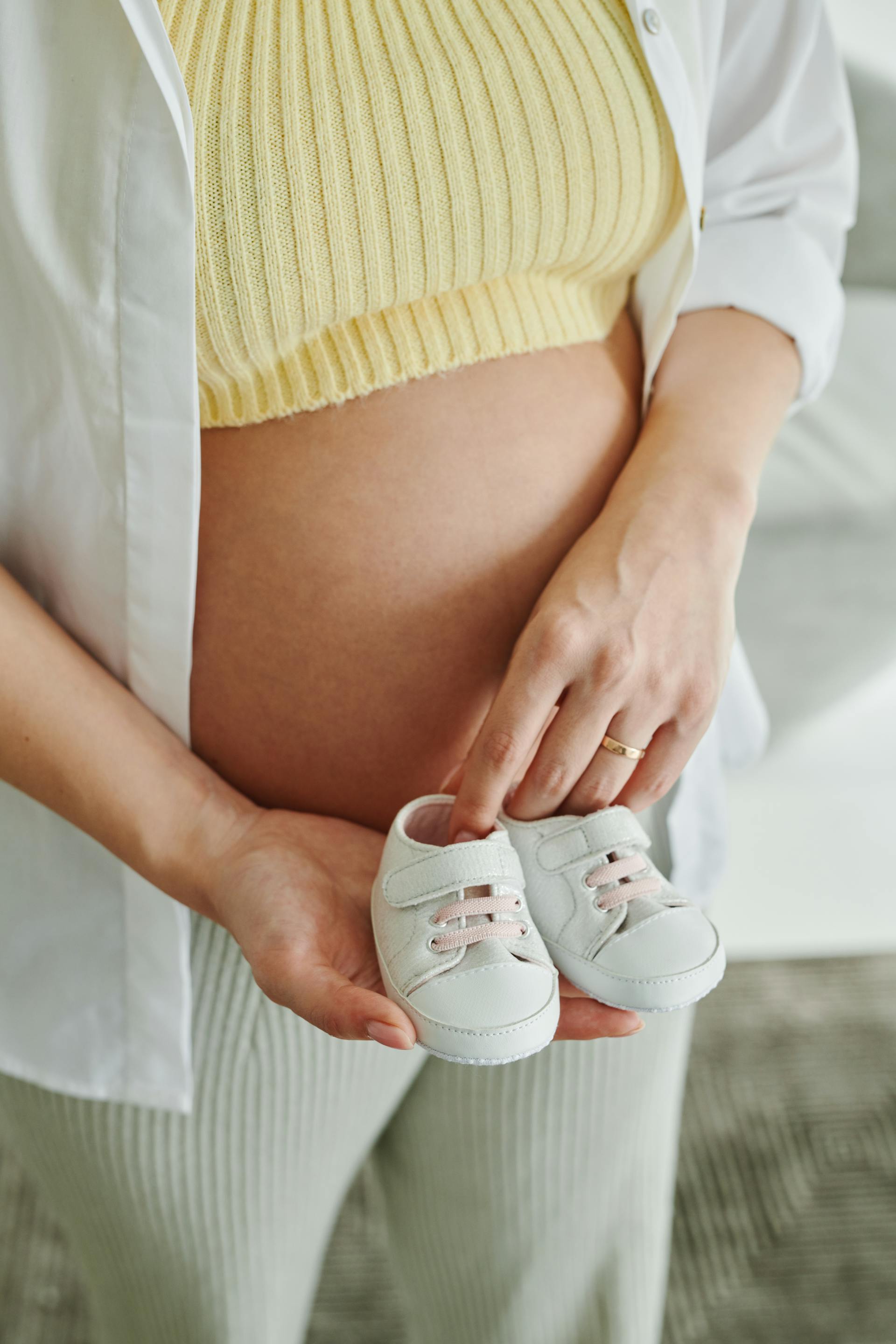 Une femme enceinte tenant des chaussures de bébé | Source : Pexels
