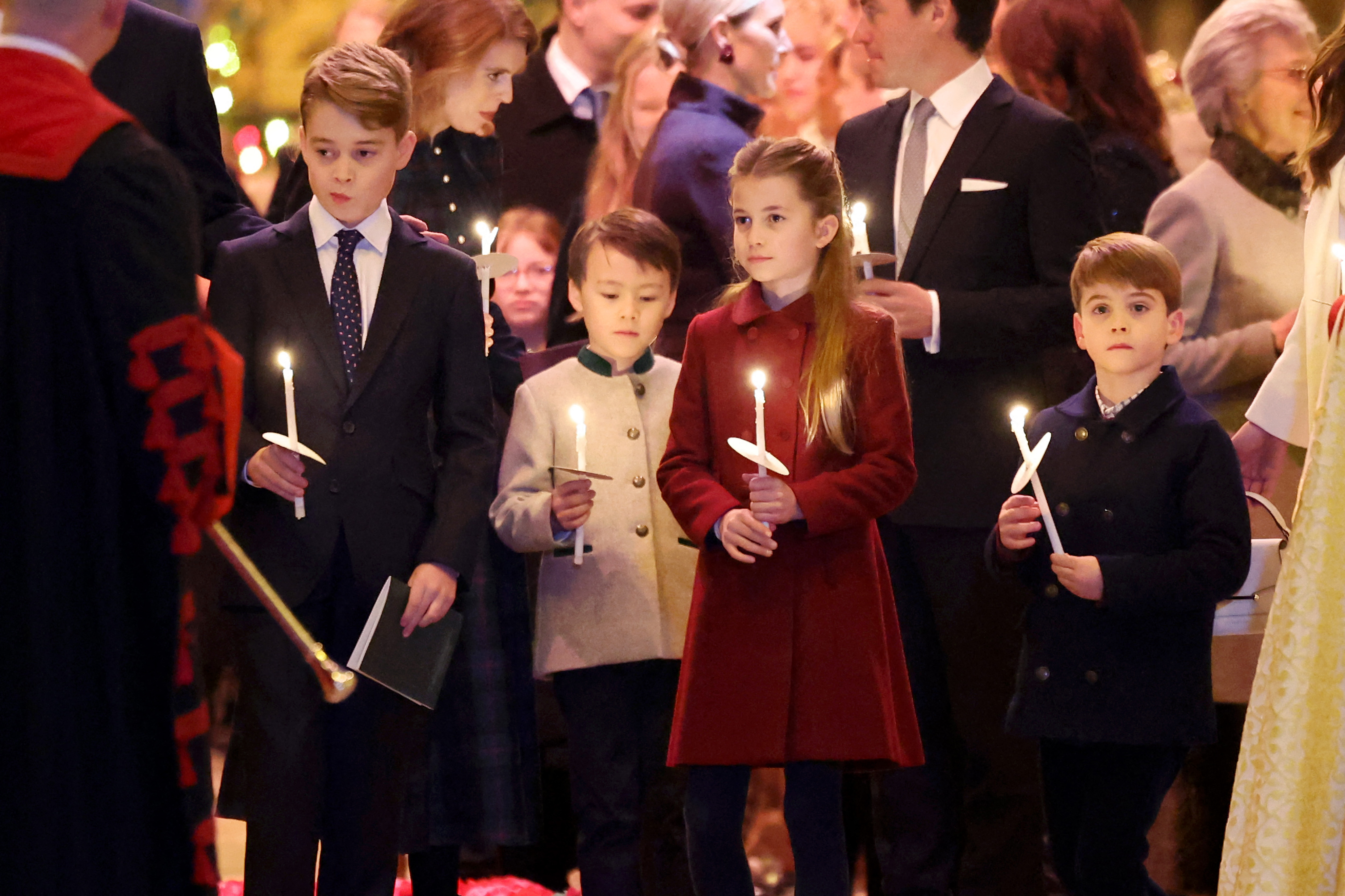 Le prince George, Christopher Woolf Mapelli Mozzi, la princesse Charlotte et le prince Louis tiennent des bougies allumées lors du service de chants "Together At Christmas" à l'abbaye de Westminster, le 8 décembre 2023, à Londres. | Source : Getty Images
