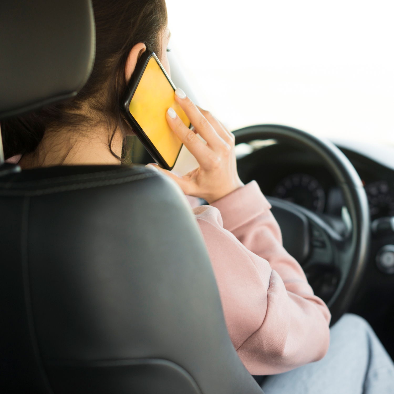 Une femme qui parle au téléphone alors qu'elle est assise au volant | Source : Freepik