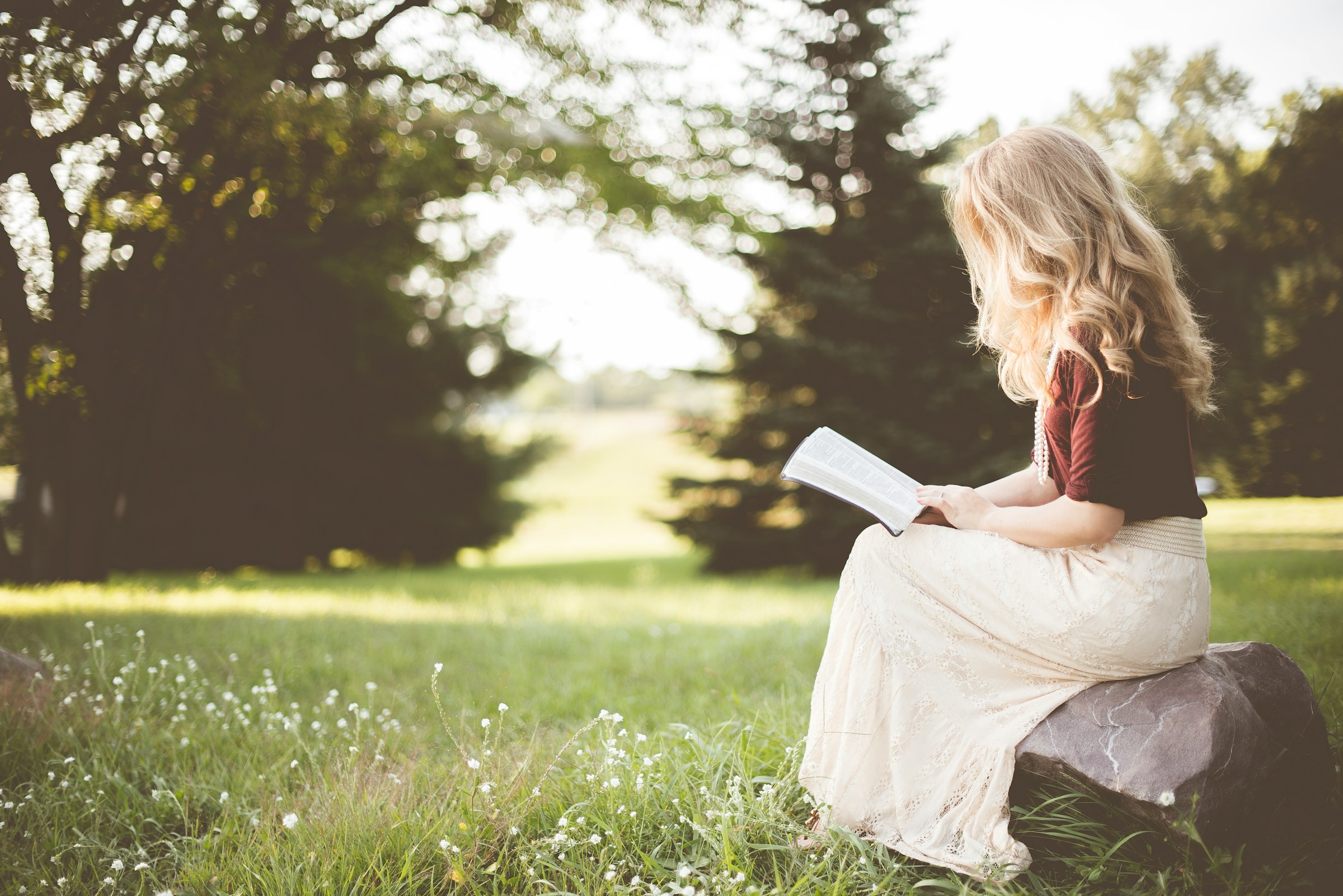 Une femme assise sur un rocher et lisant un livre | Source : Unsplash