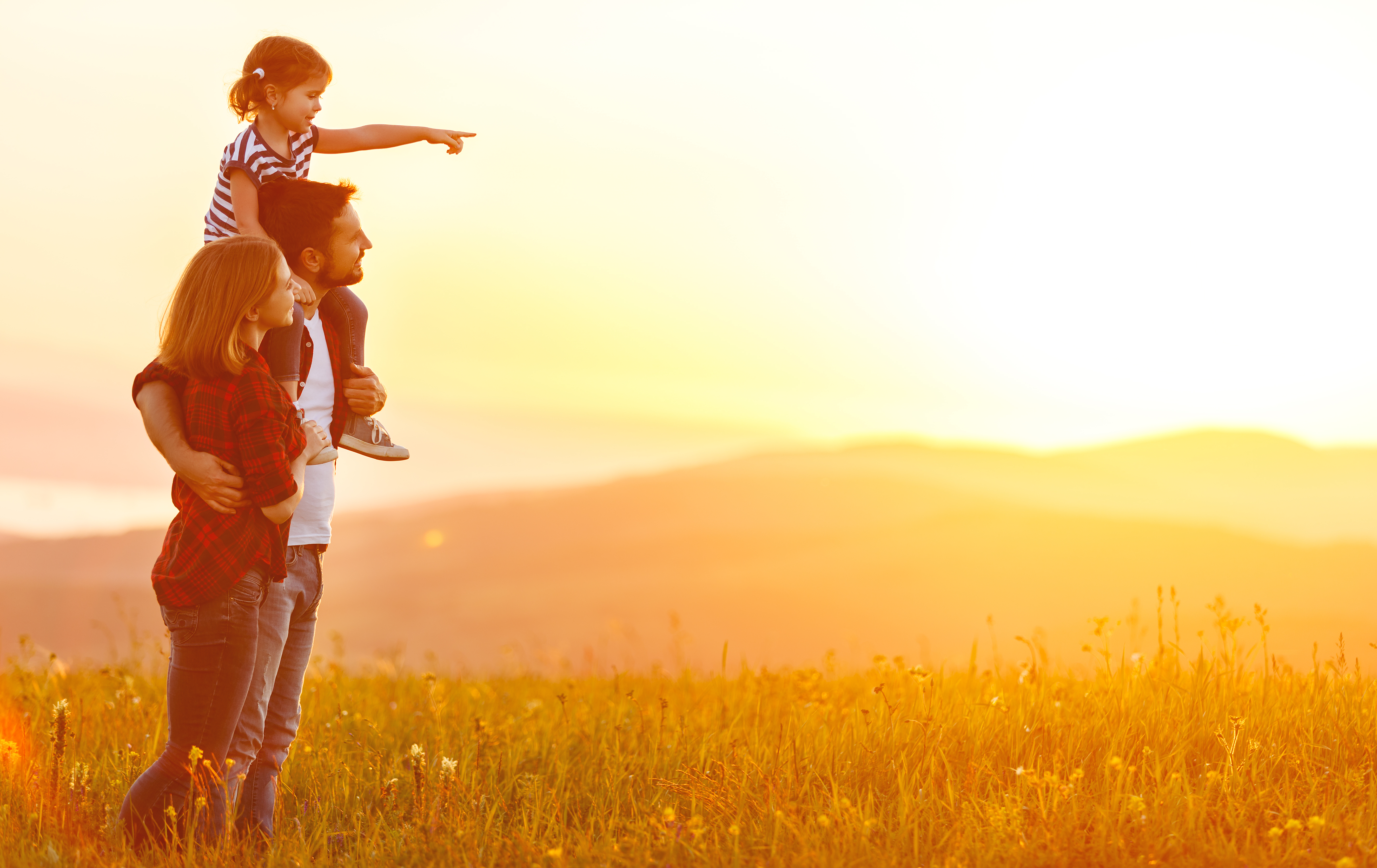 Couple regardant le coucher de soleil avec leur petite fille | Source : Shutterstock