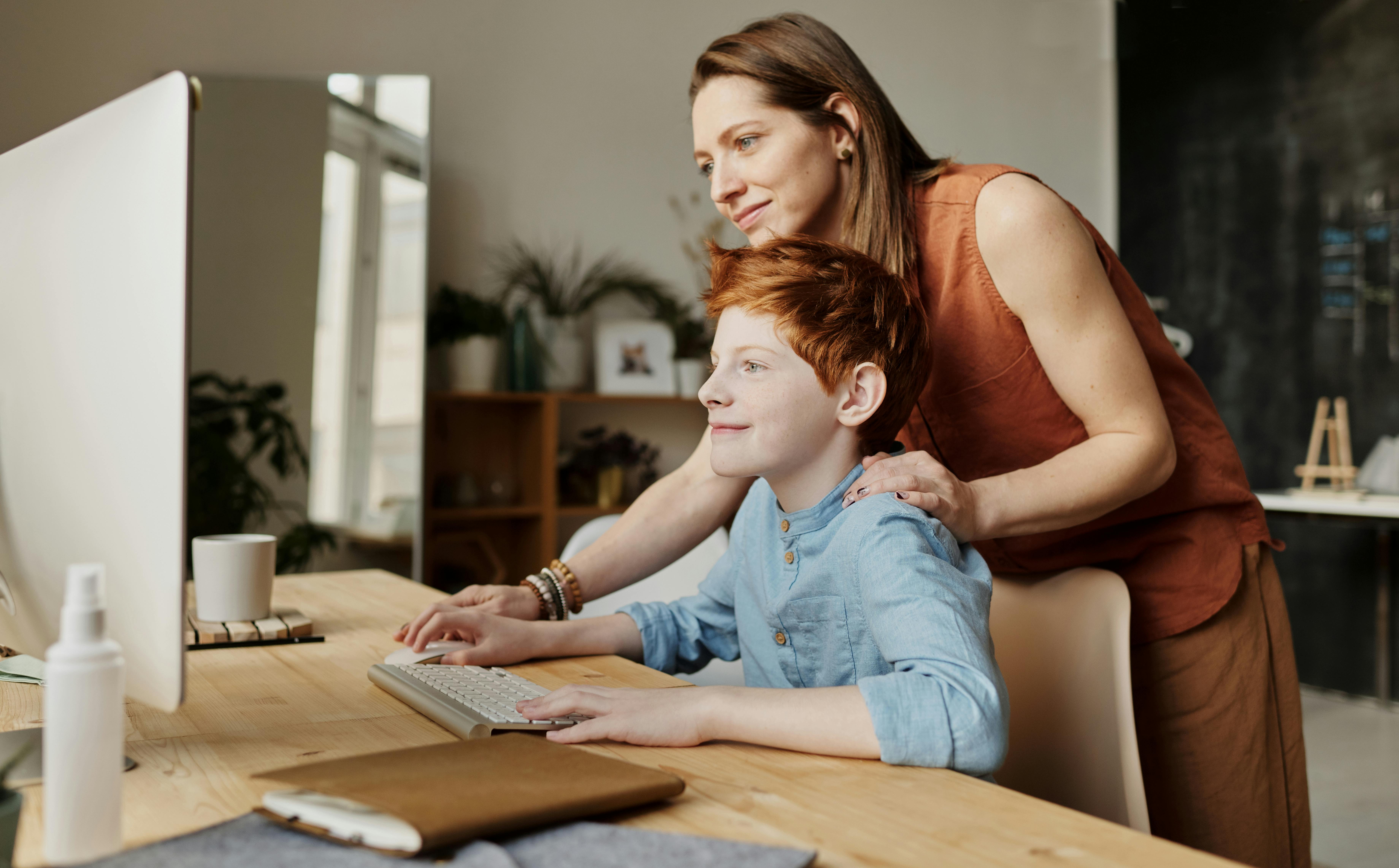 Une femme avec un garçon travaillant sur un ordinateur | Source : Pexels