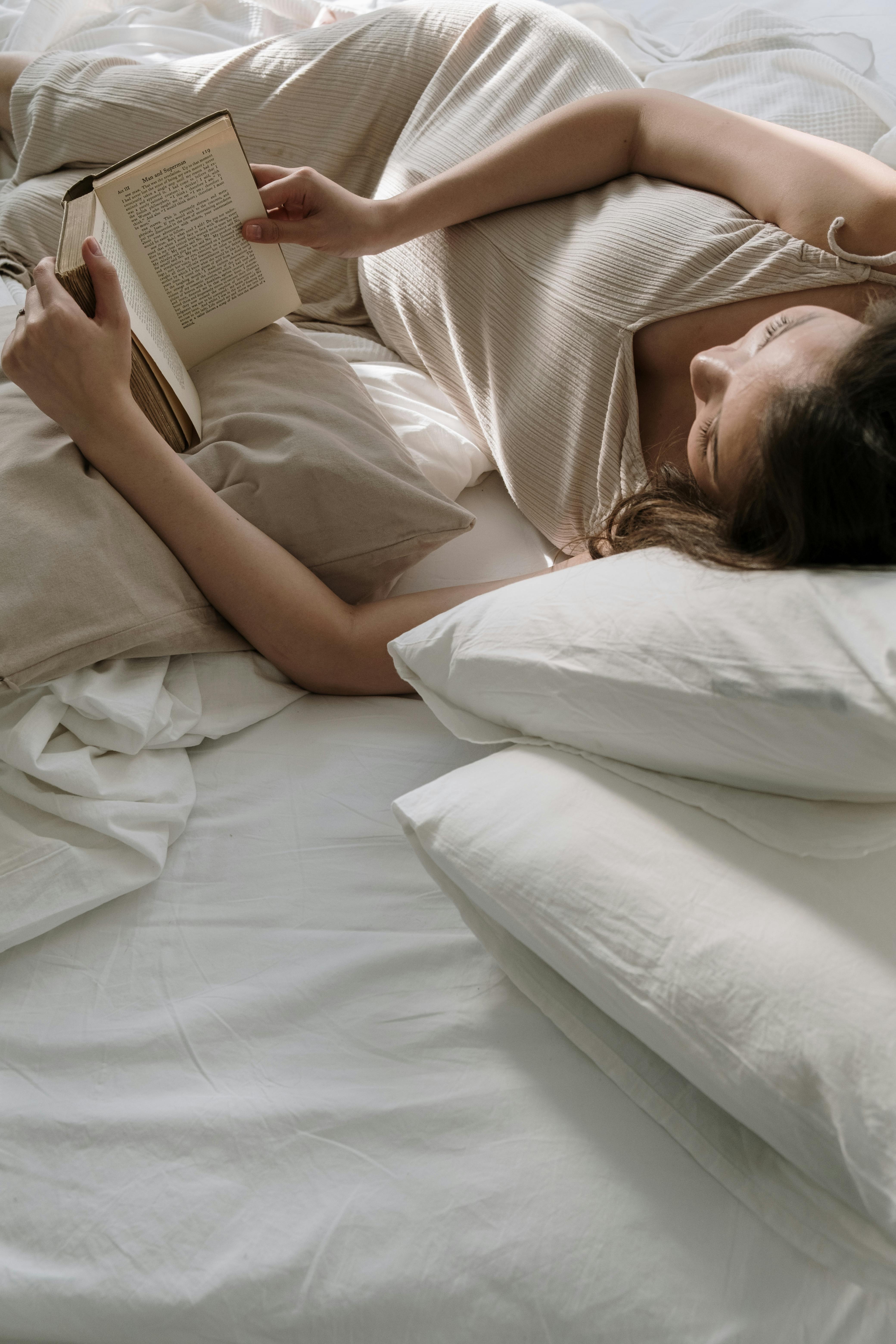 Une femme allongée dans son lit en train de lire un livre | Source : Pexels