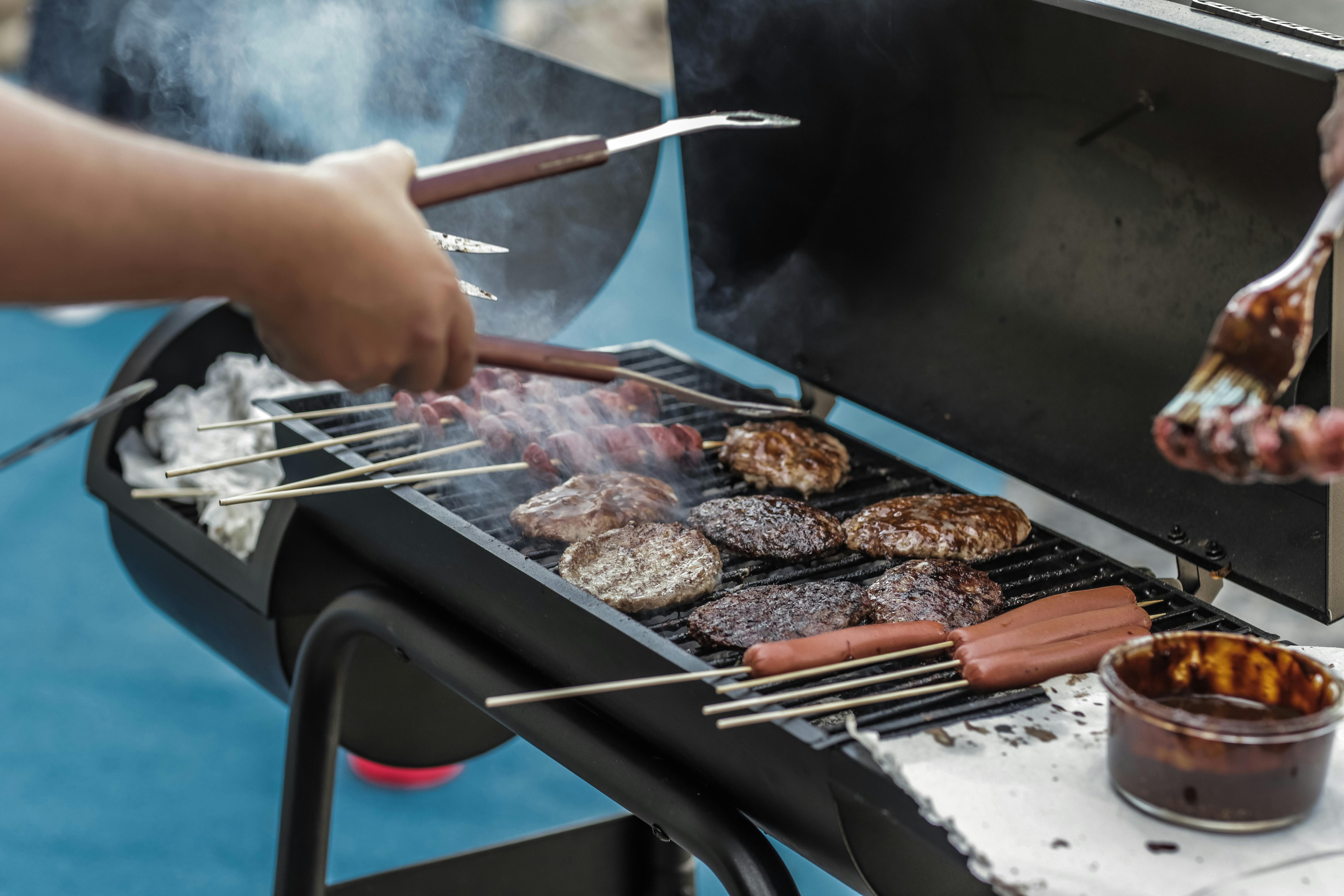 Un homme fait griller des saucisses et de la viande | Source : Pexels