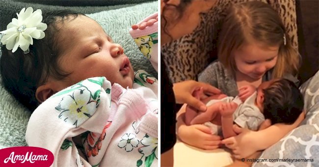 Une petite fille est émue en portant pour la première fois son cousin nouveau-né