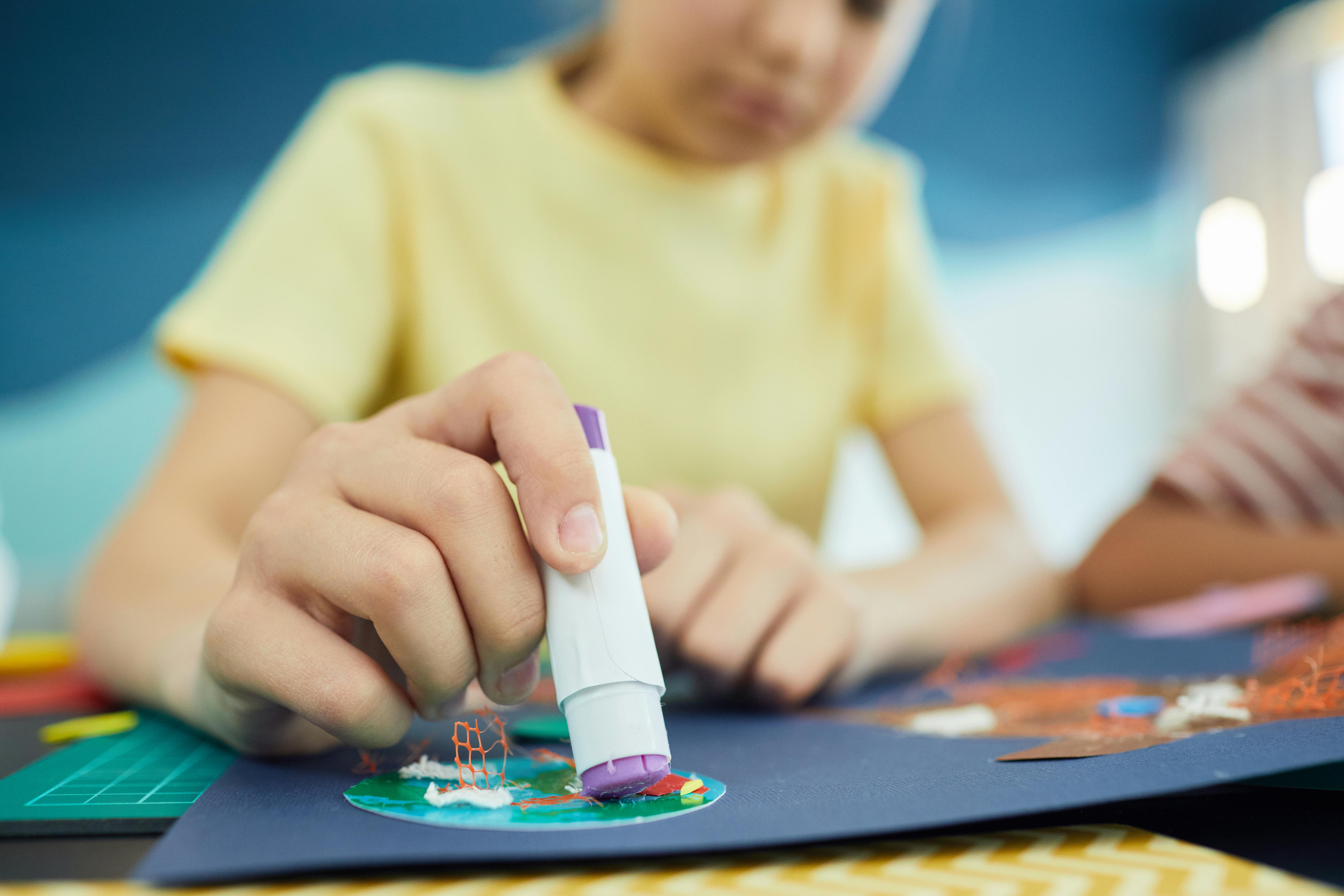 Un enfant utilisant un bâton de colle | Source : Pexels