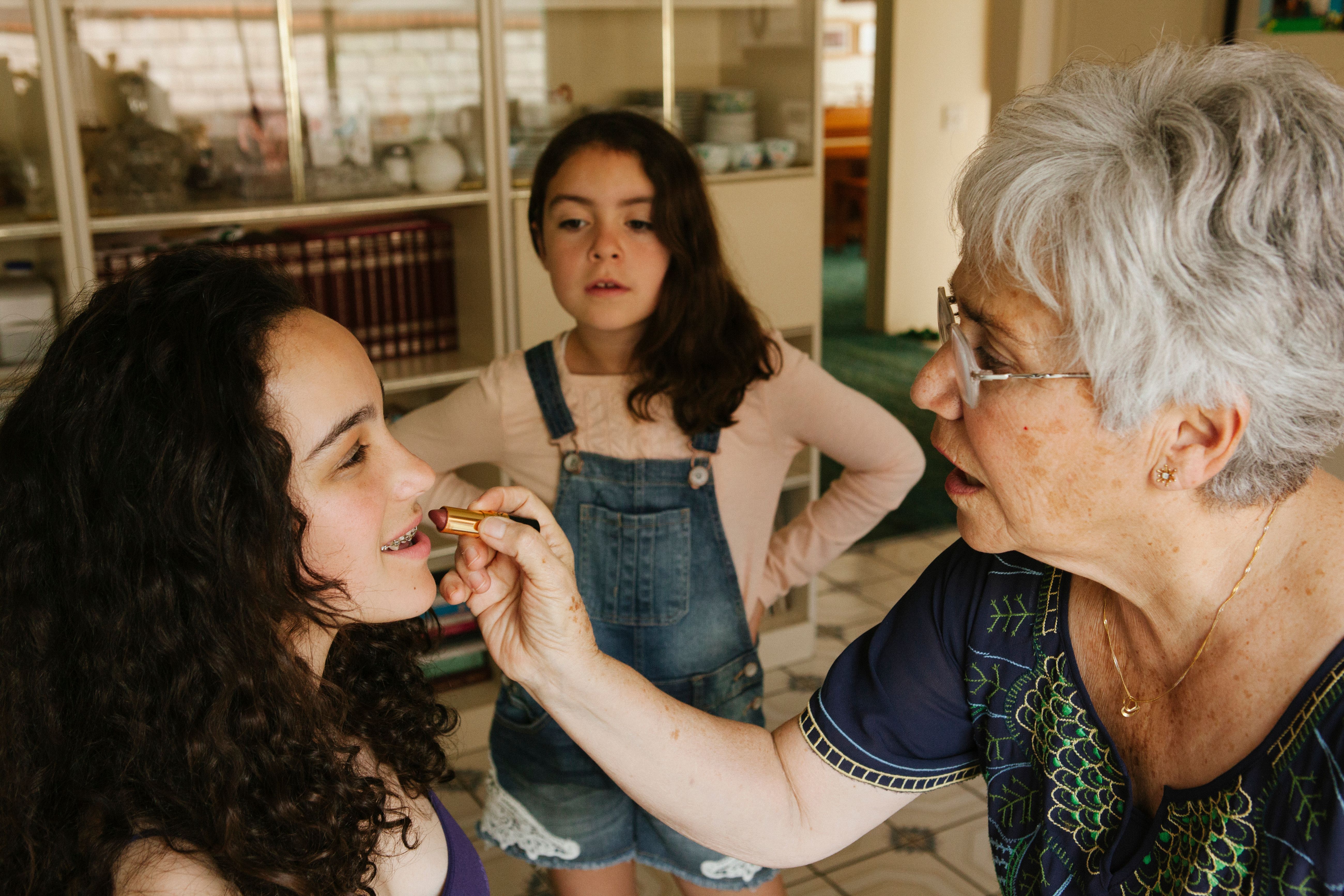 Une grand-mère mettant du rouge à lèvres à sa petite-fille | Source : Getty Images