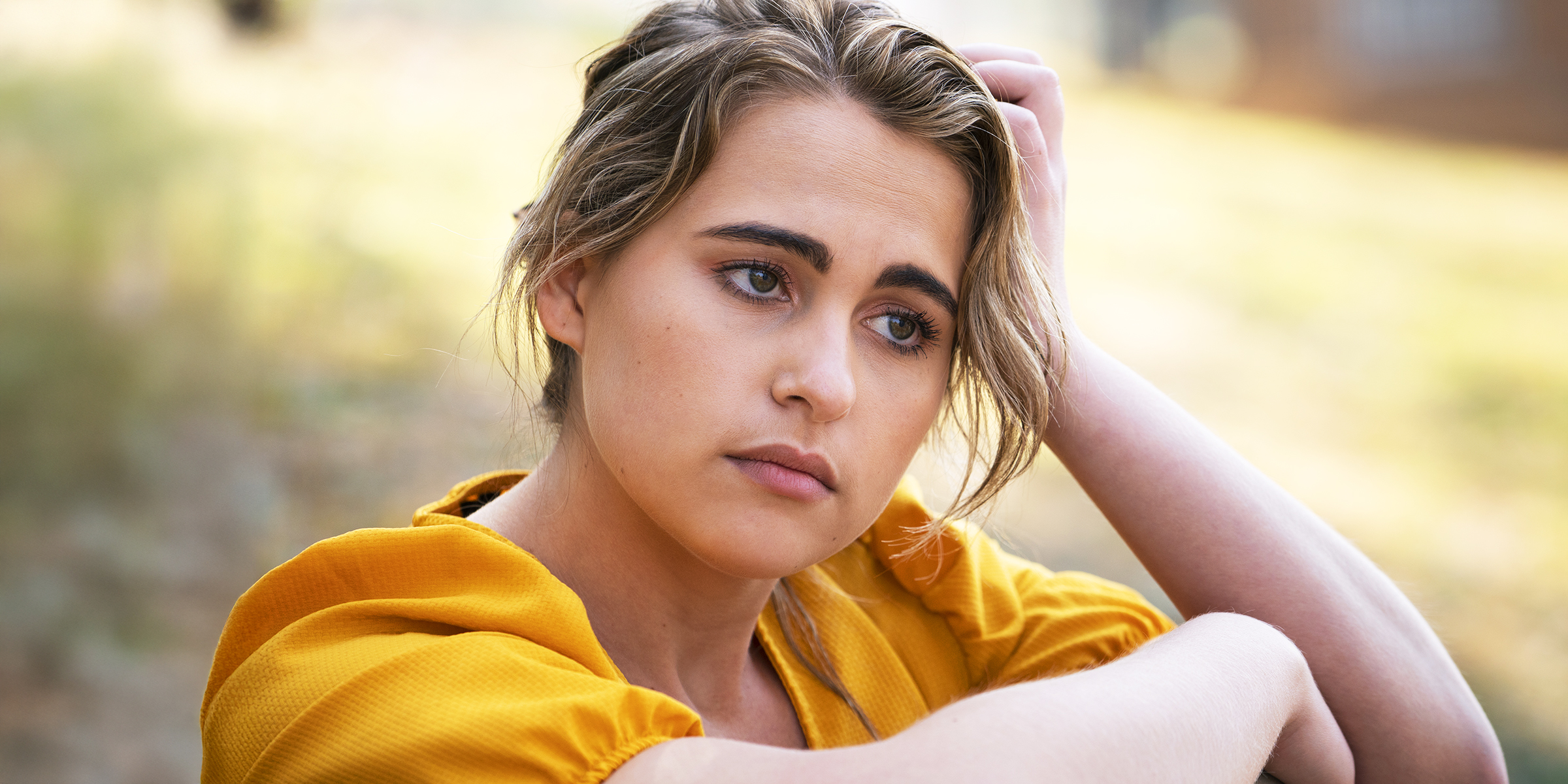 Une jeune femme en robe jaune perdue dans ses pensées | Source : Freepik