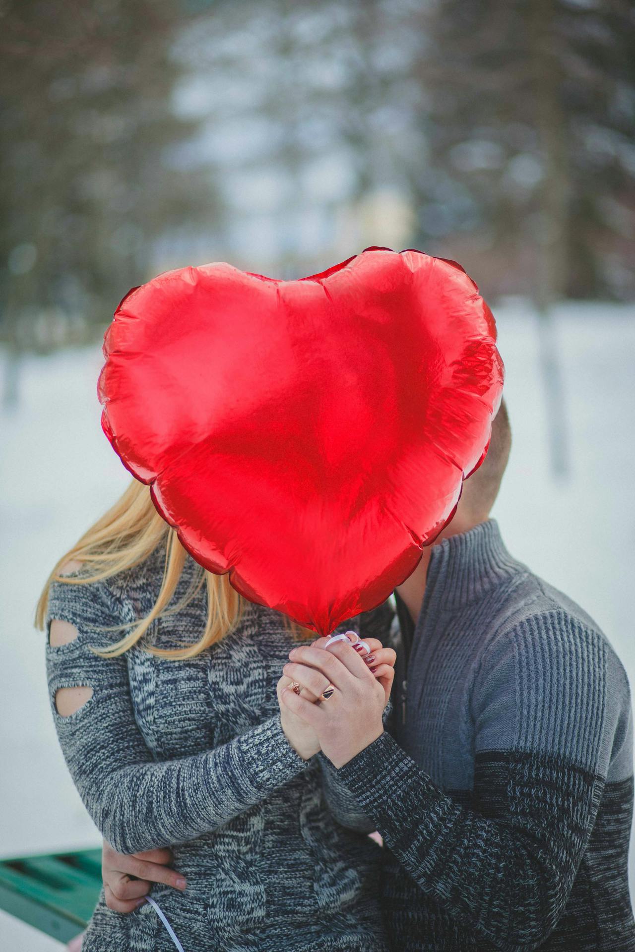Un couple romantique tenant un ballon rouge en forme de cœur | Source : Pexels