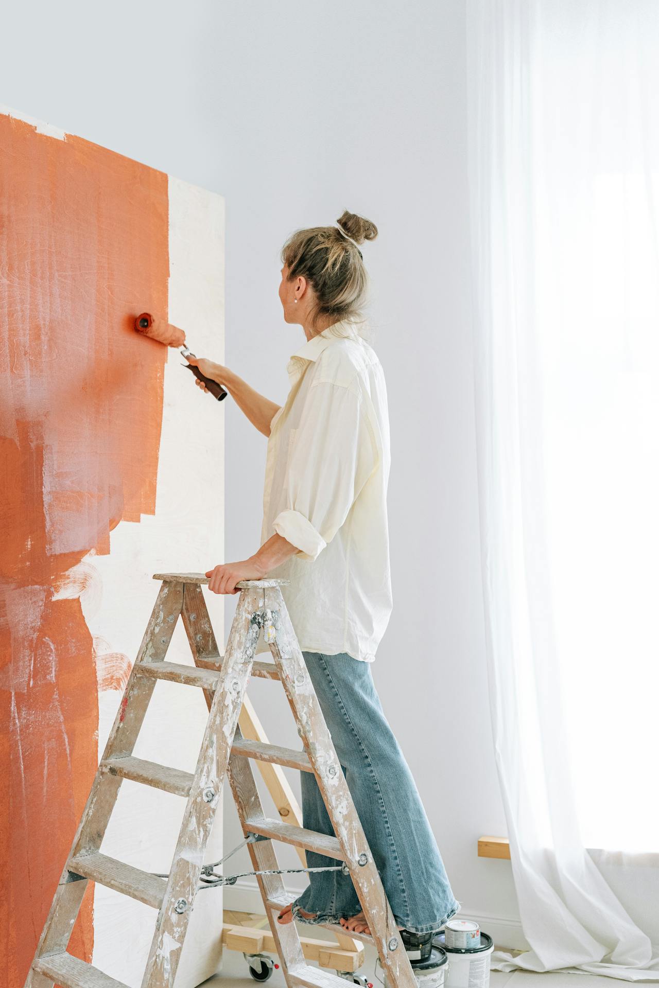 Une femme debout sur une échelle et peignant un mur | Source : Pexels