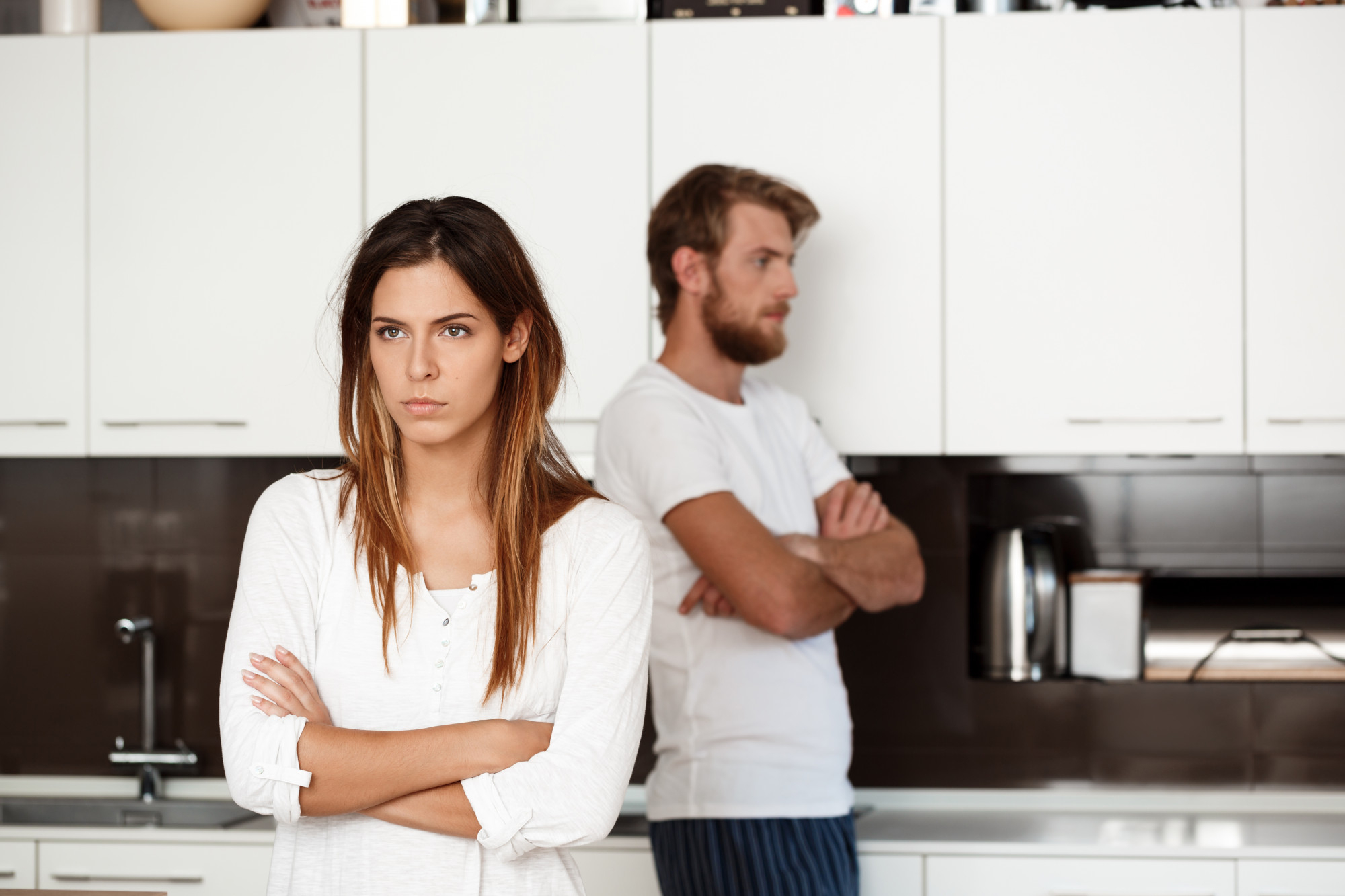 Un couple en désaccord se tenant à distance l'un de l'autre dans une cuisine | Source : Freepik