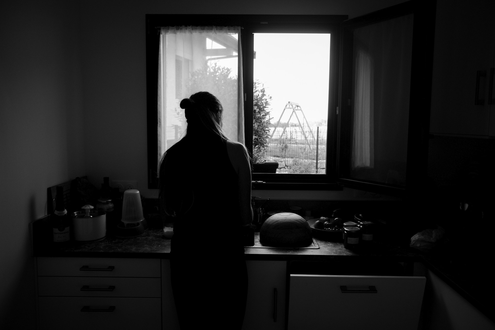 Photo en niveaux de gris d'une femme debout dans la cuisine | Source : Unsplash