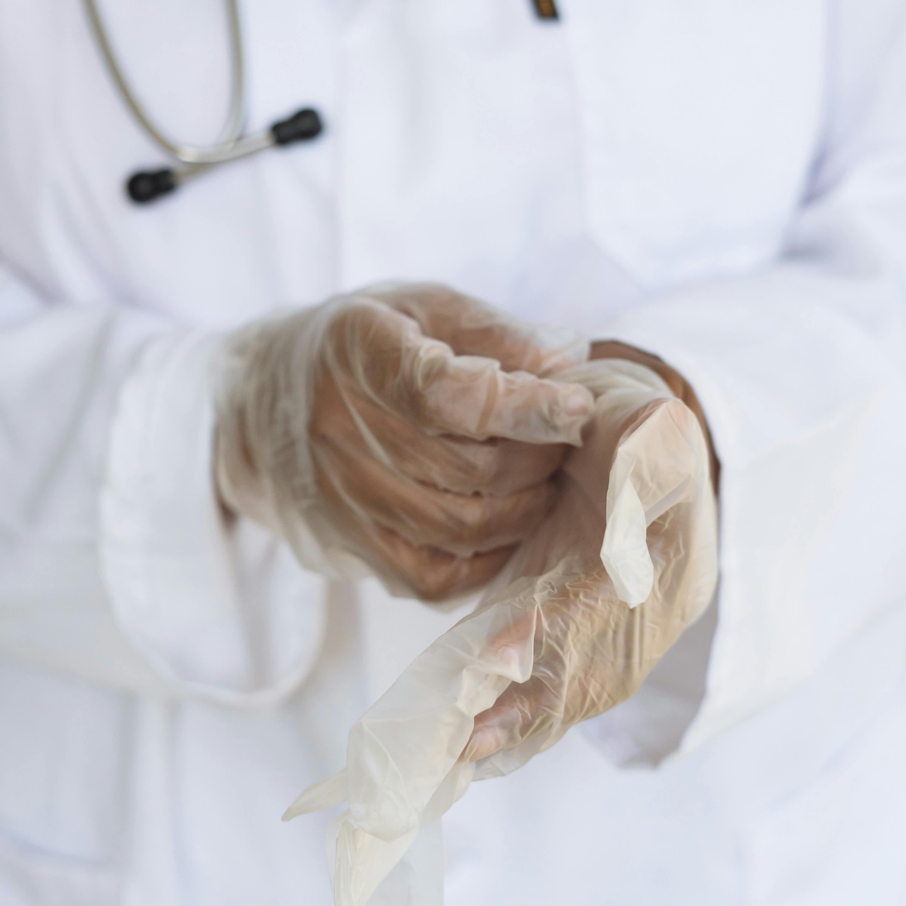 Un professionnel de la santé enfilant des gants en latex | Source : Pexels