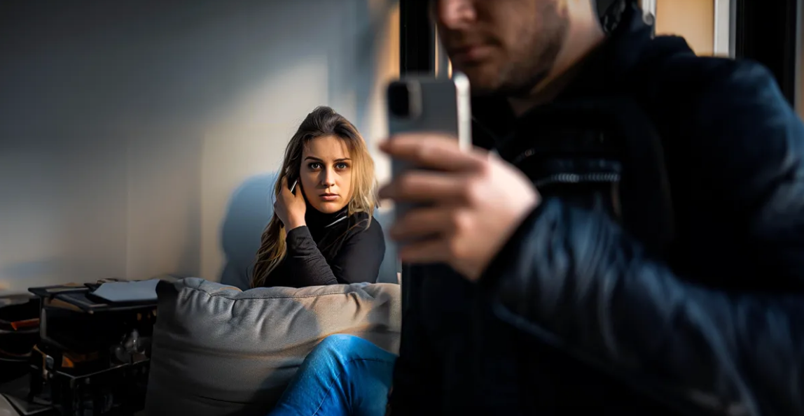 Femme espionnant derrière un homme avec un téléphone | Source : Shutterstock