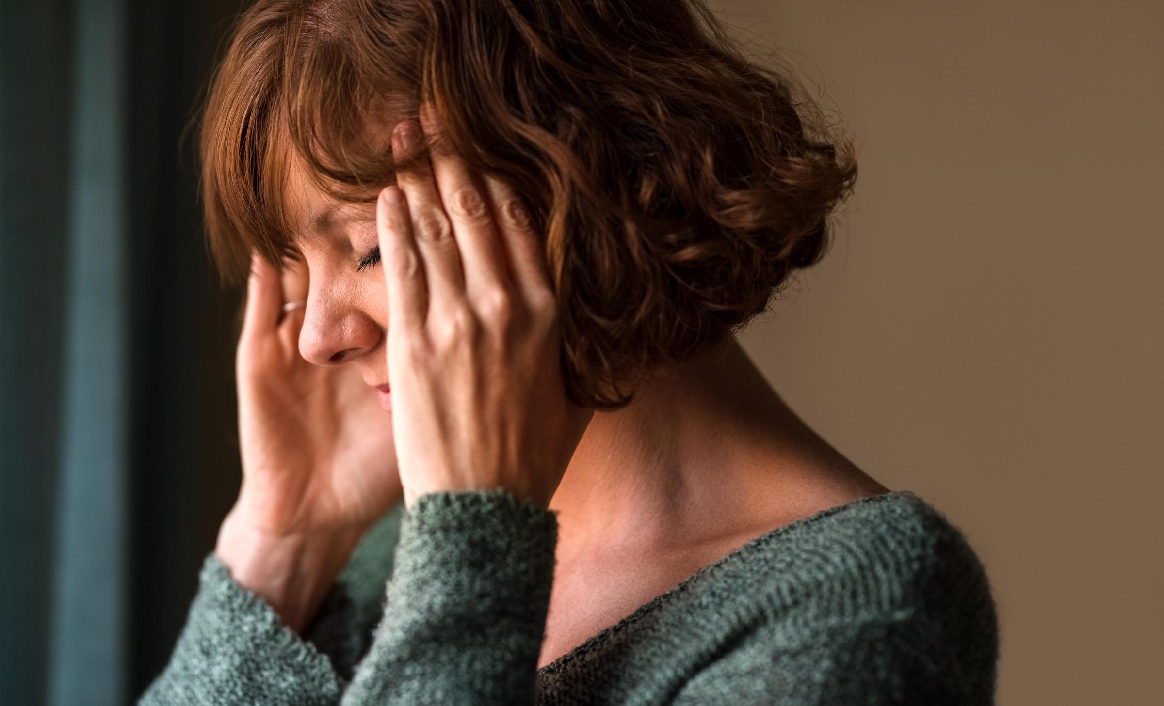 Femme souffrant d'un mal de tête, se frottant les tempes en signe d'inconfort | Source : Getty Images