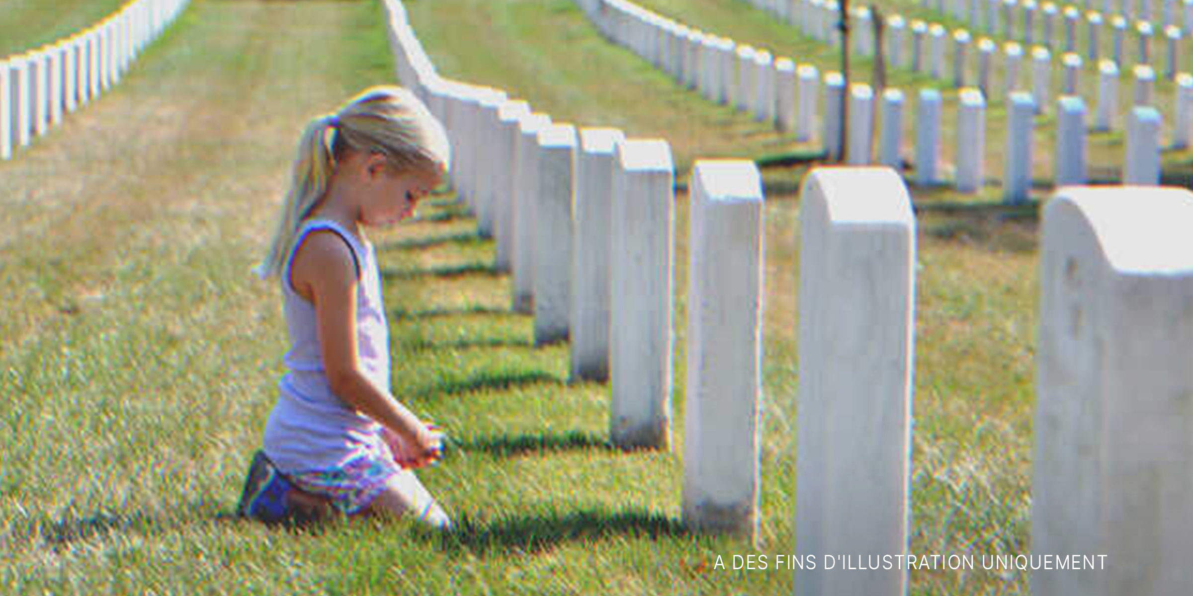 Une petite fille à genoux devant une tombe | Source : Shutterstock.com