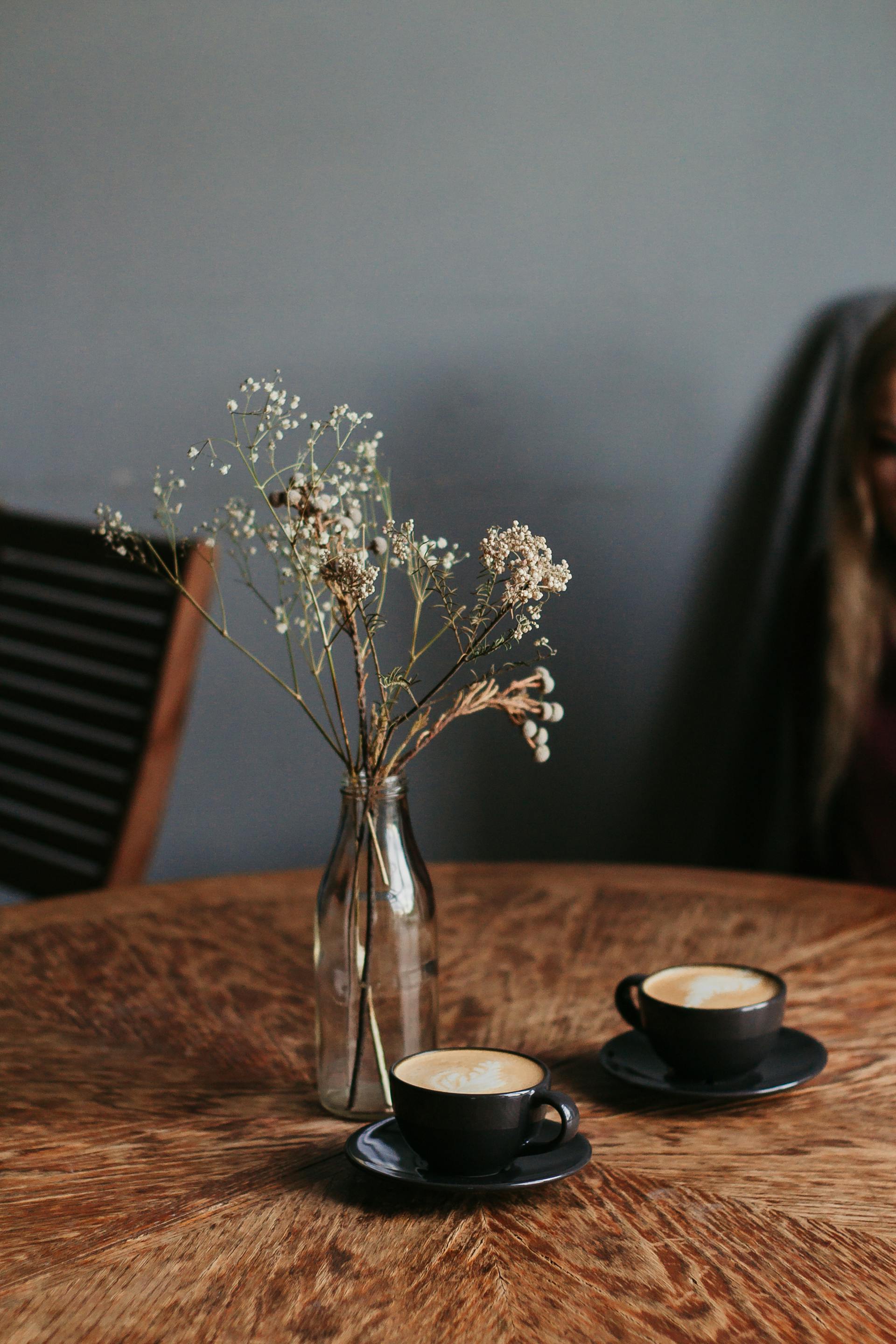 Deux tasses de café près d'un vase de fleurs sur une table | Source : Pexels