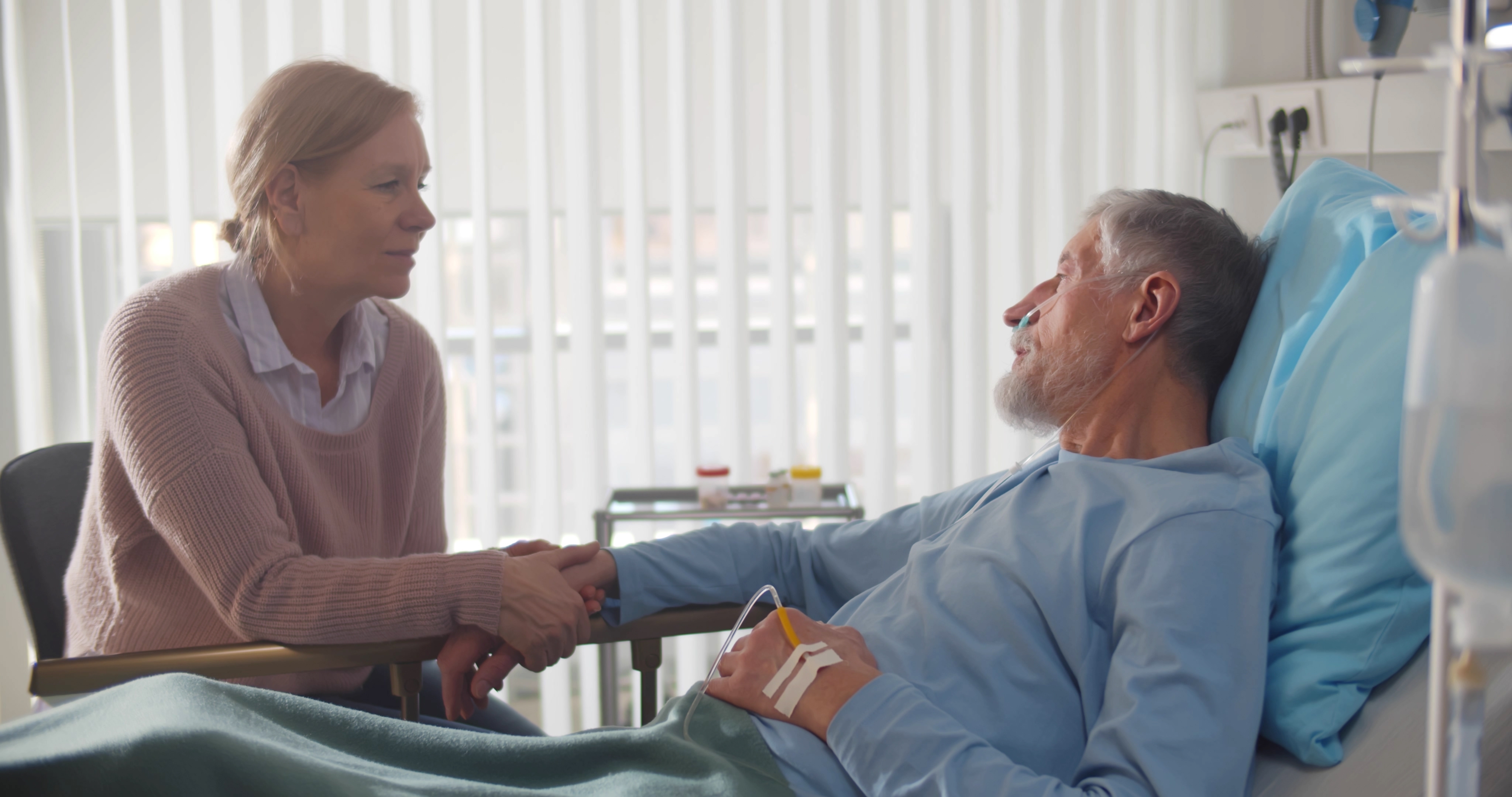 Une femme attentionnée tenant la main de son mari malade à l'hôpital | Source : Shutterstock