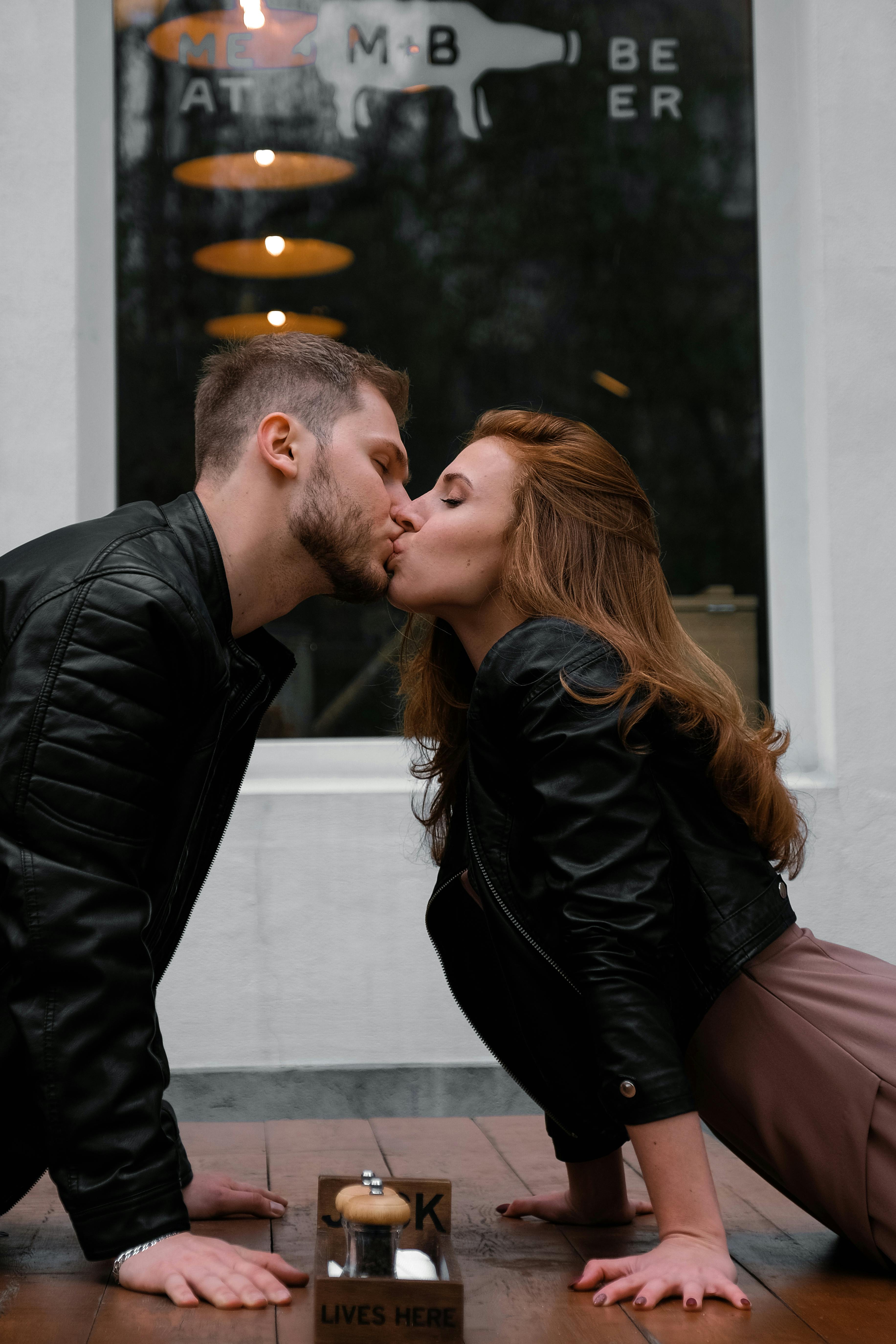 Un homme et une femme s'embrassant au-dessus d'une table | Source : Pexels