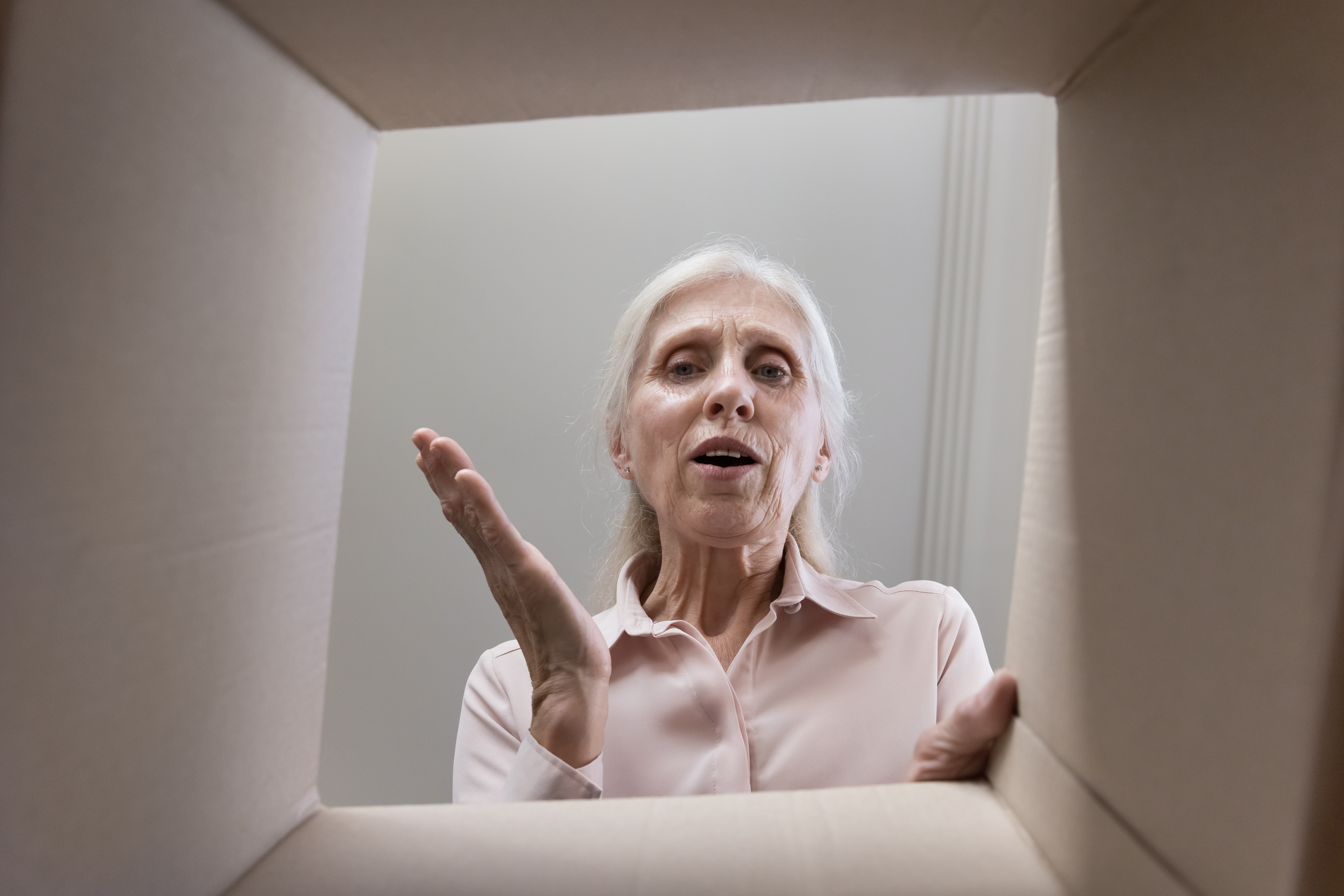 Femme âgée regardant à l'intérieur d'une boîte en carton | Source : Shutterstock