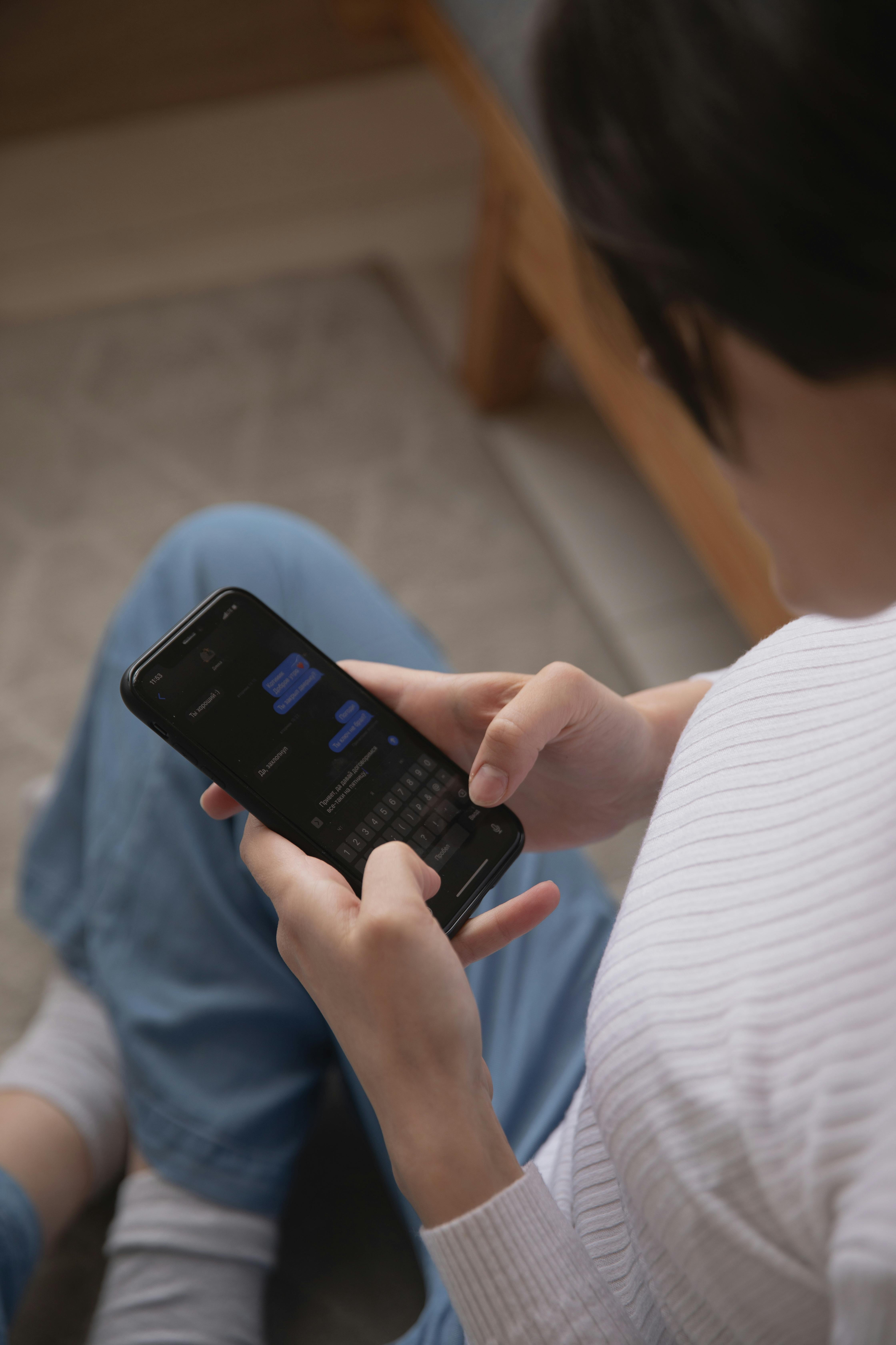 Une femme assise par terre utilisant son téléphone | Source : Pexels