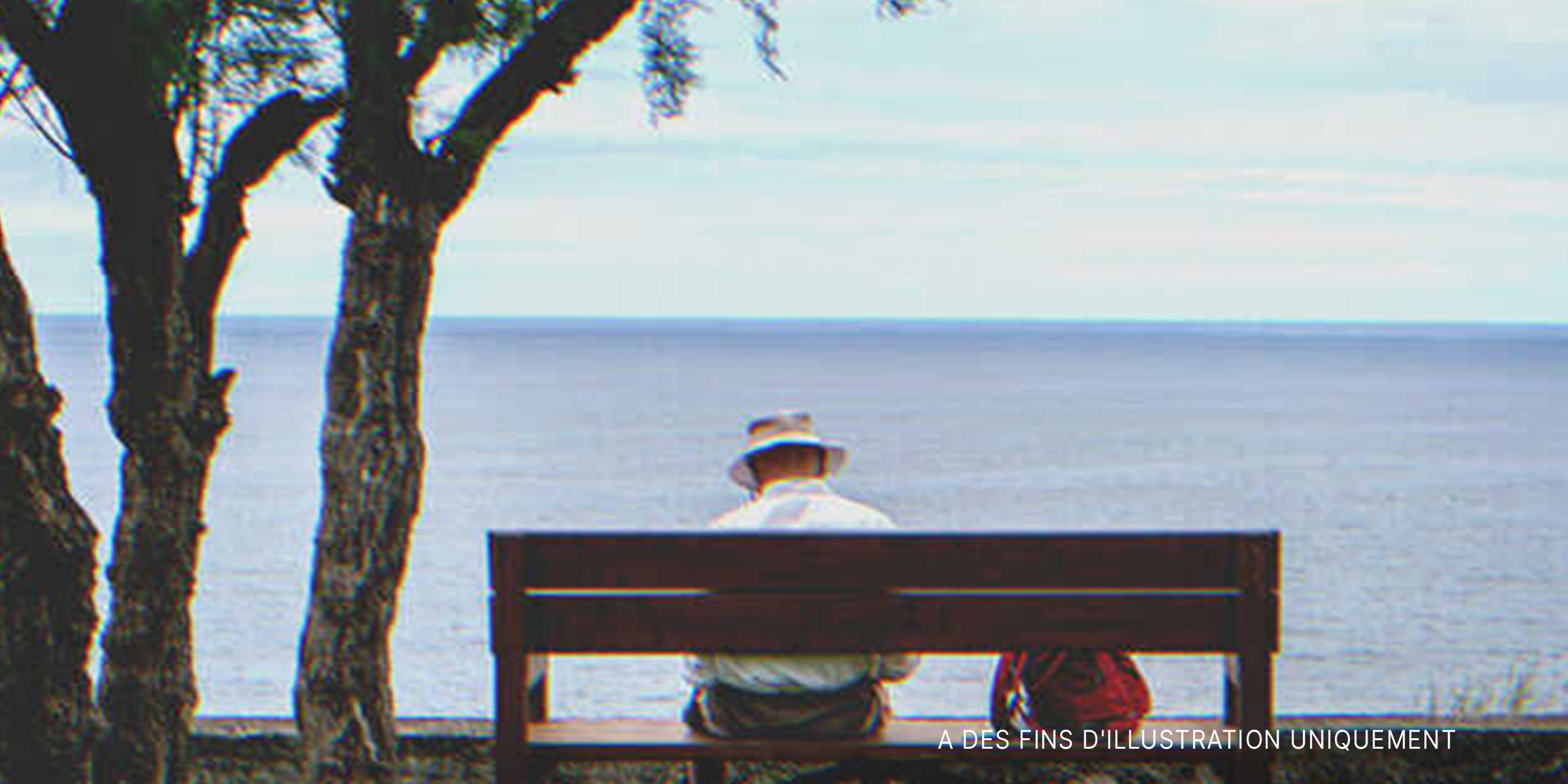 Un homme âgé assis sur banc et face à la mer | Source : Shutterstock