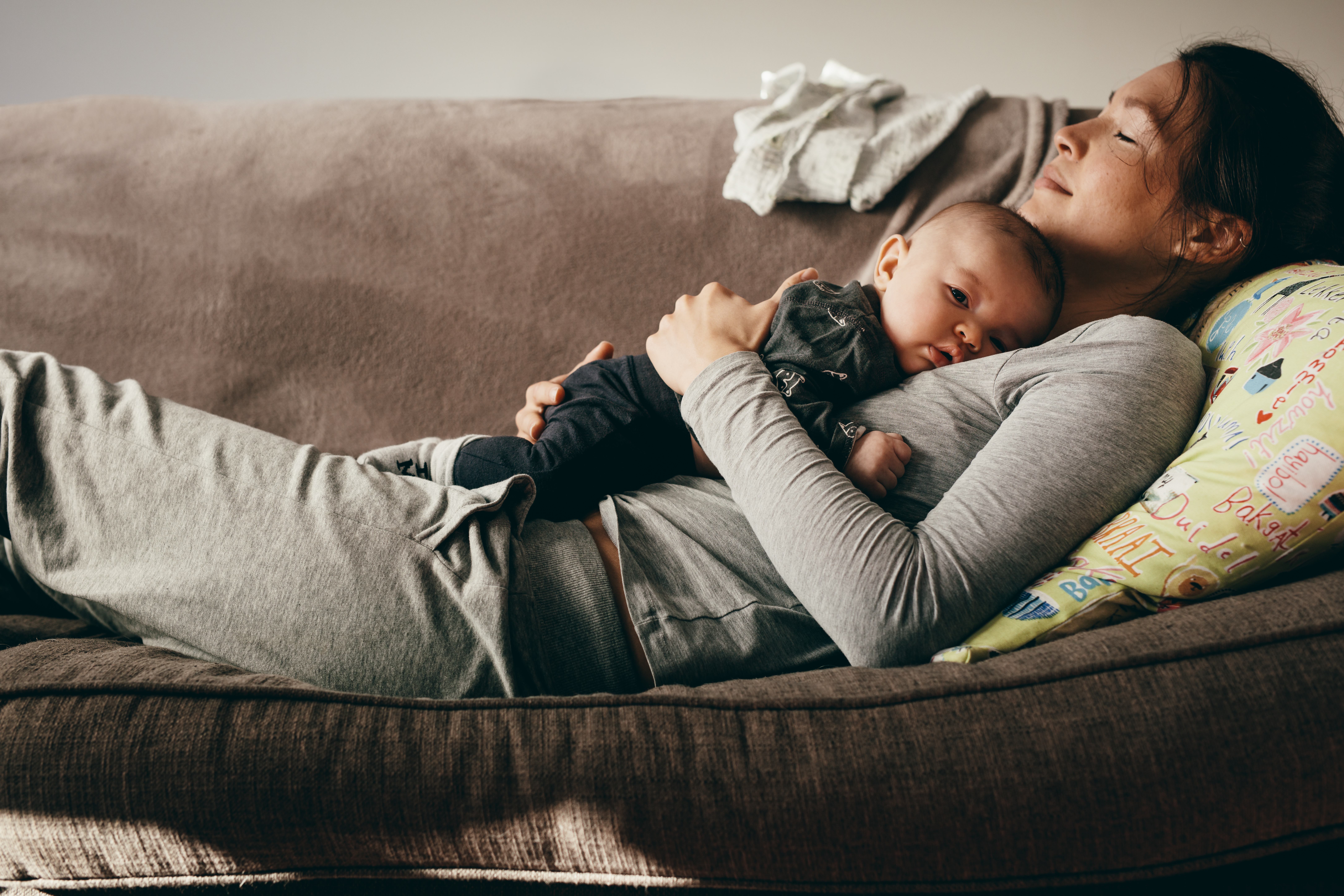 Une mère allongée sur le canapé tout en tenant un bébé | Source : Shutterstock