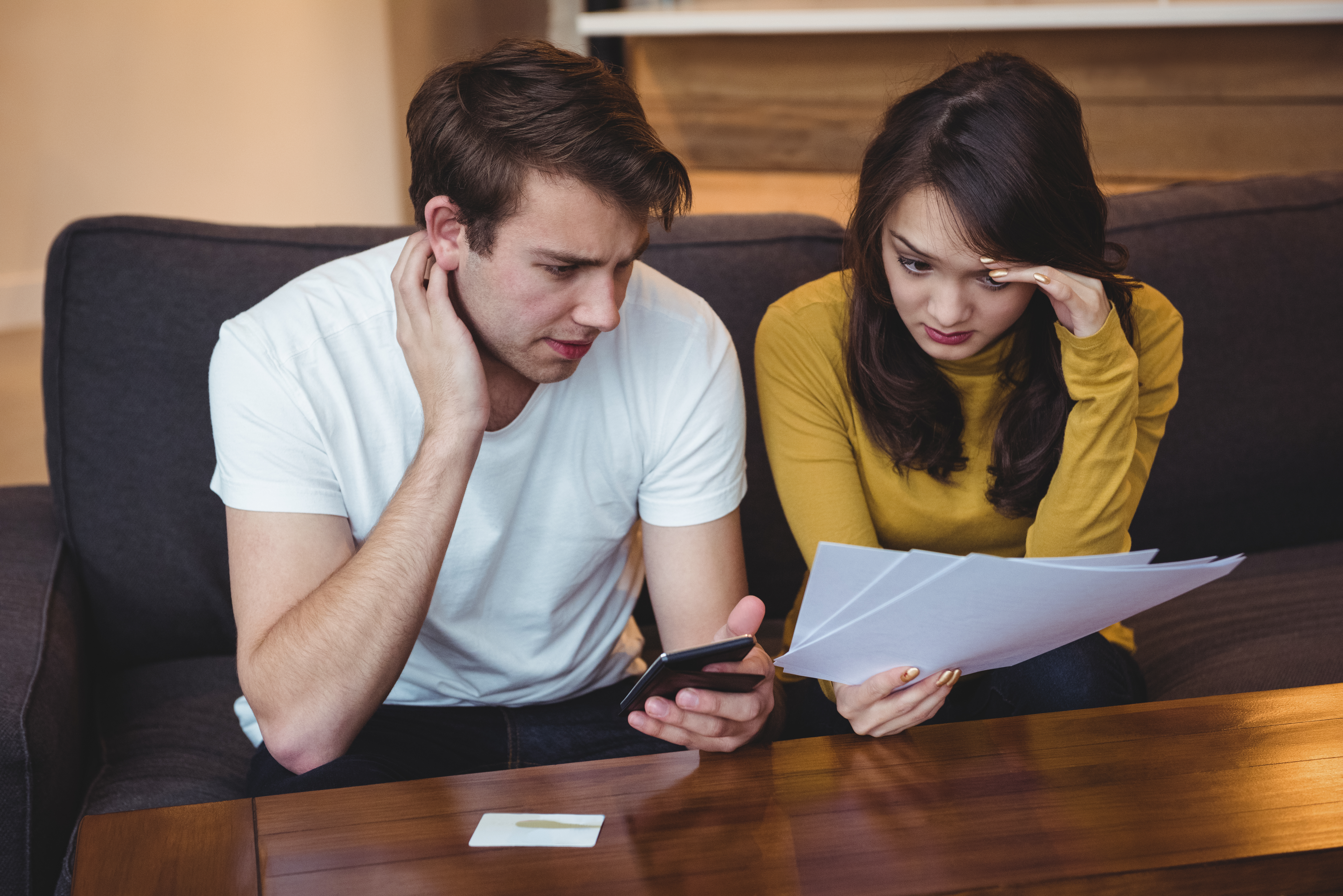 Deux personnes sur un canapé et regardant des documents | Source : Freepik