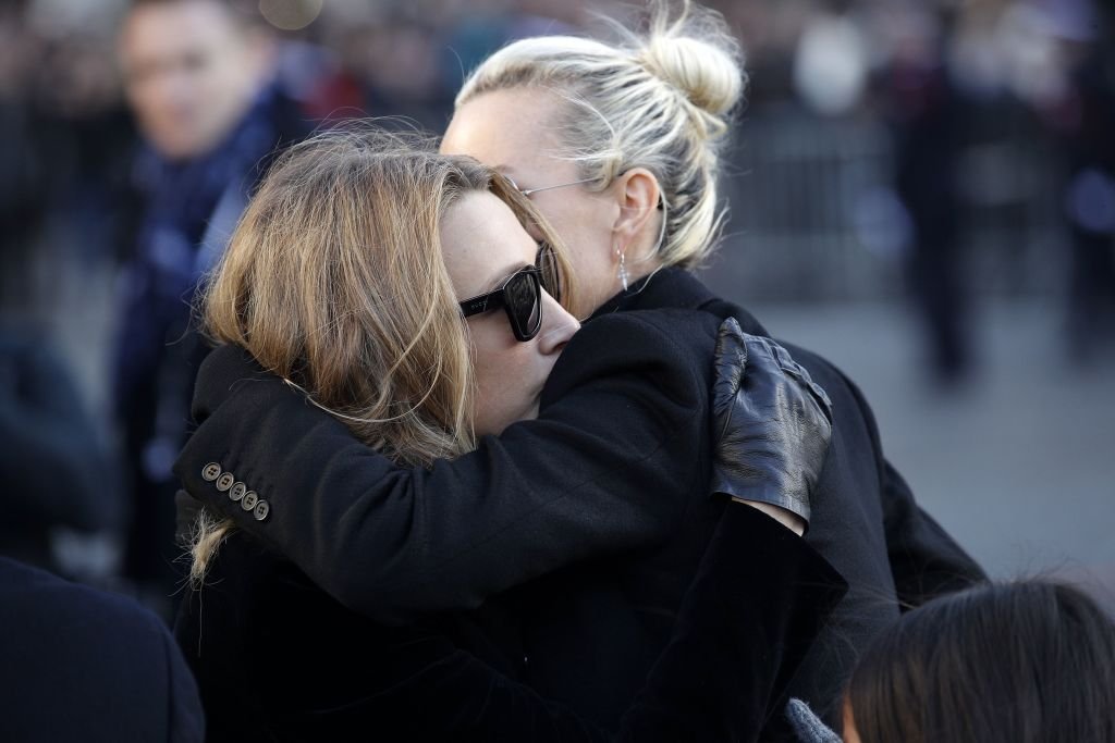 L'épouse du défunt chanteur français Johnny Hallyday étreint Laura Smet lors de la cérémonie de funérailles de Hallyday devant l'église de la Madeleine à Paris, le 9 décembre 2017. | Photo : Getty Images