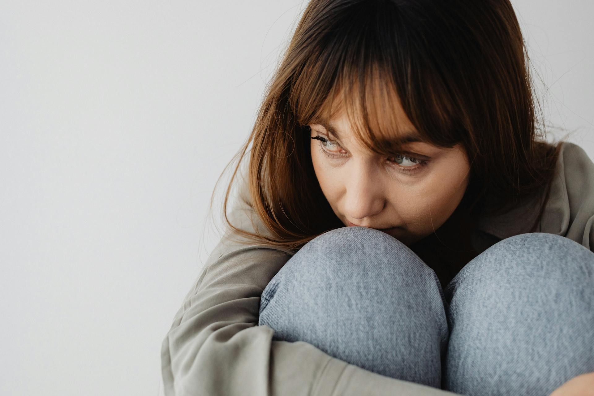 Une femme en détresse recroquevillée sur la chaise et regardant sur le côté | Source : Pexels