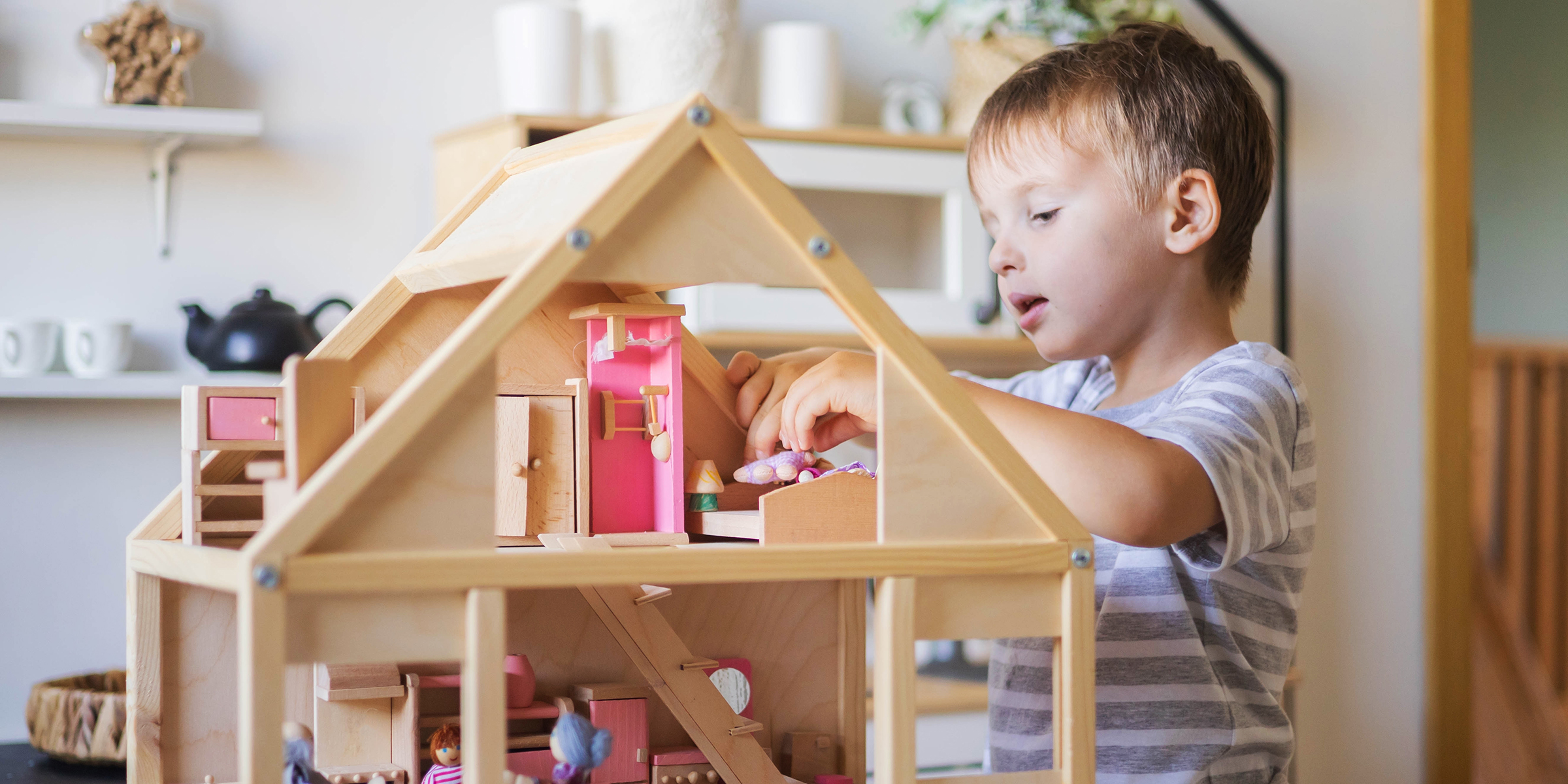 Un garçon qui joue avec une maison de poupée | Source : Shutterstock