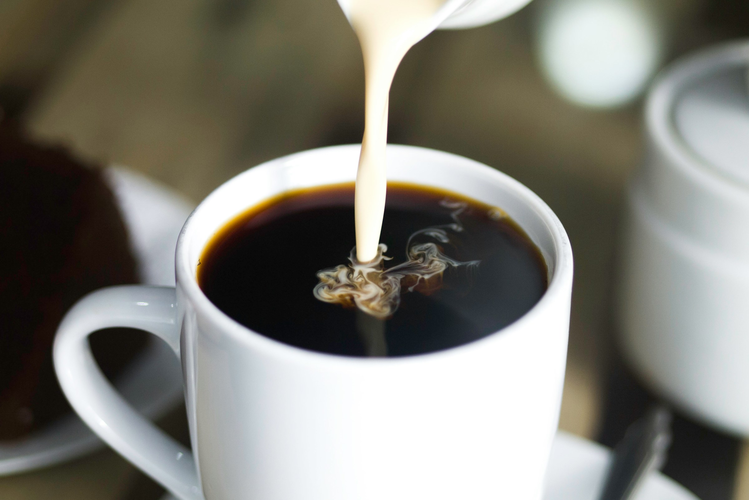 Une personne versant du lait dans du café | Source : Unsplash