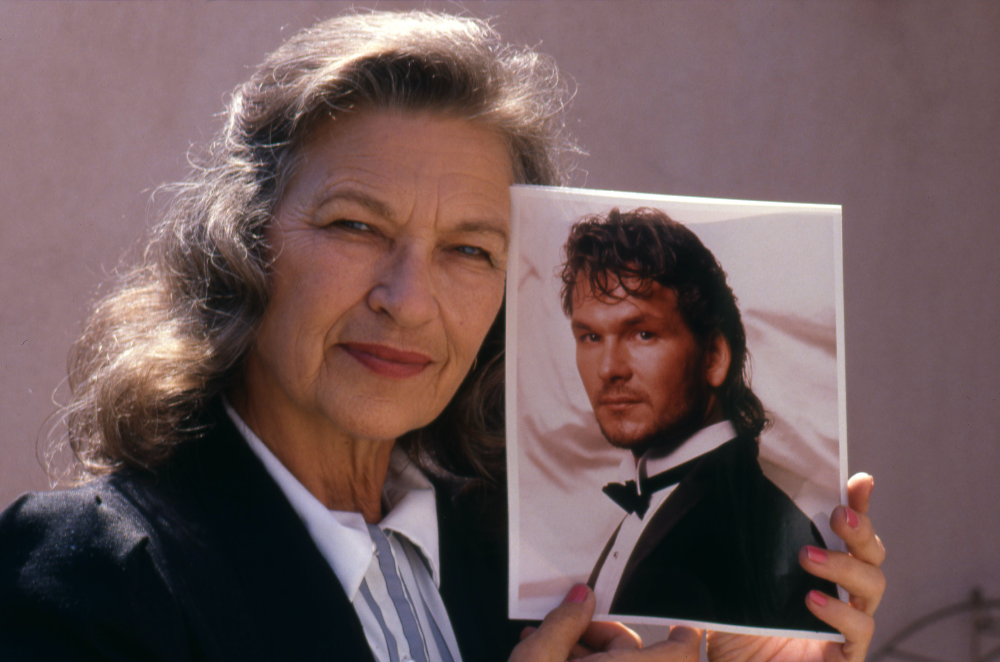 Patsy Swayze pose pour un portrait en tenant une photo de son fils, Patrick Swayze, vers 1988 | Source : Getty Images