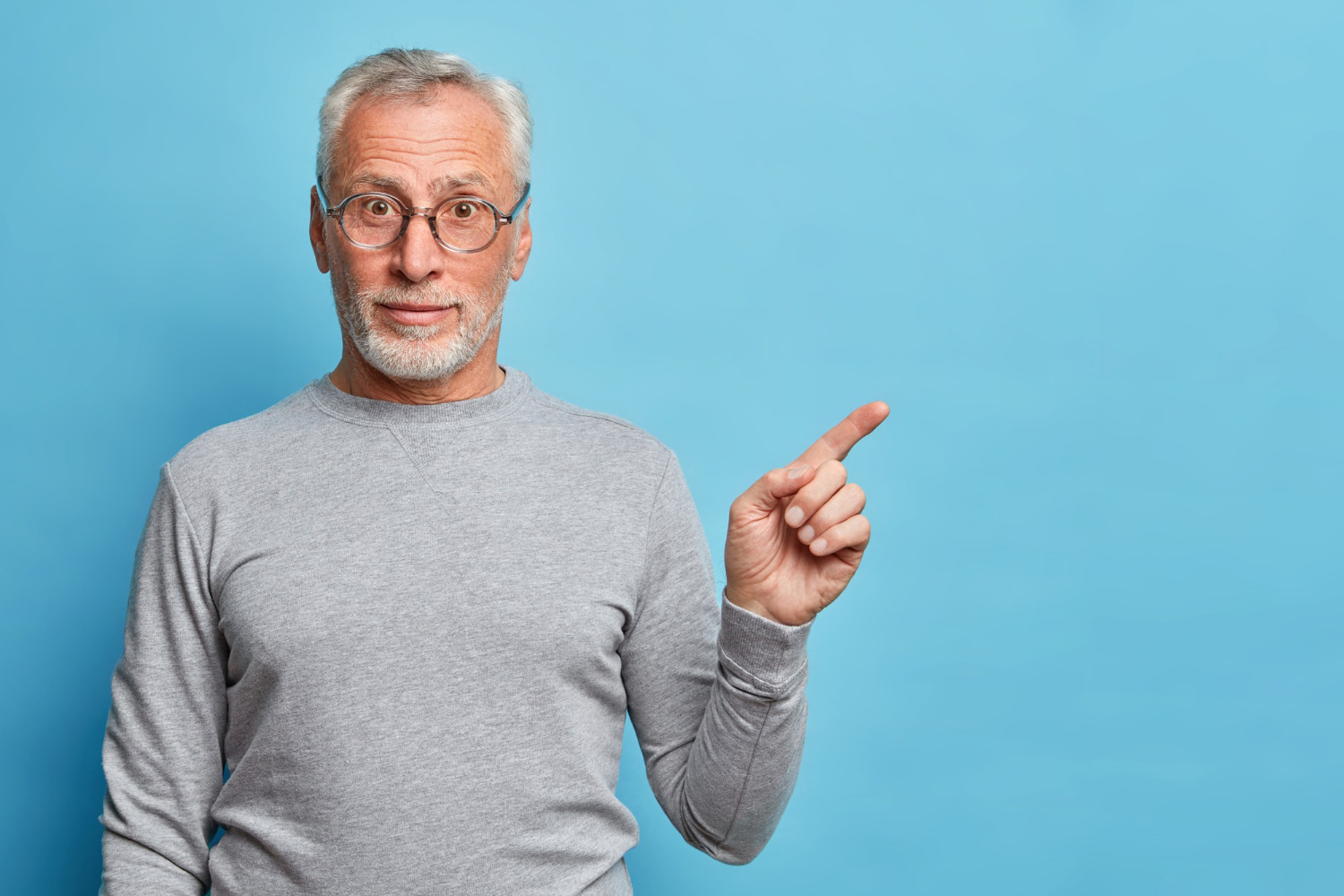 Un homme âgé souriant qui pointe son doigt | Source : Freepik