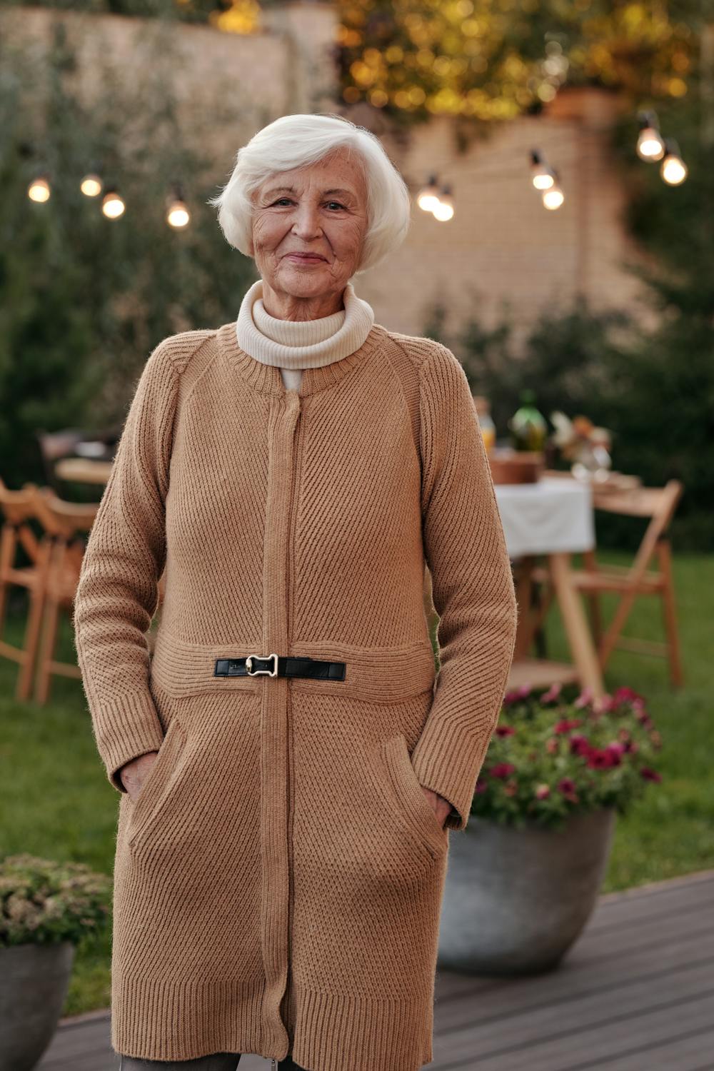 A woman smiling on her porch ⏐ Source: Pexels