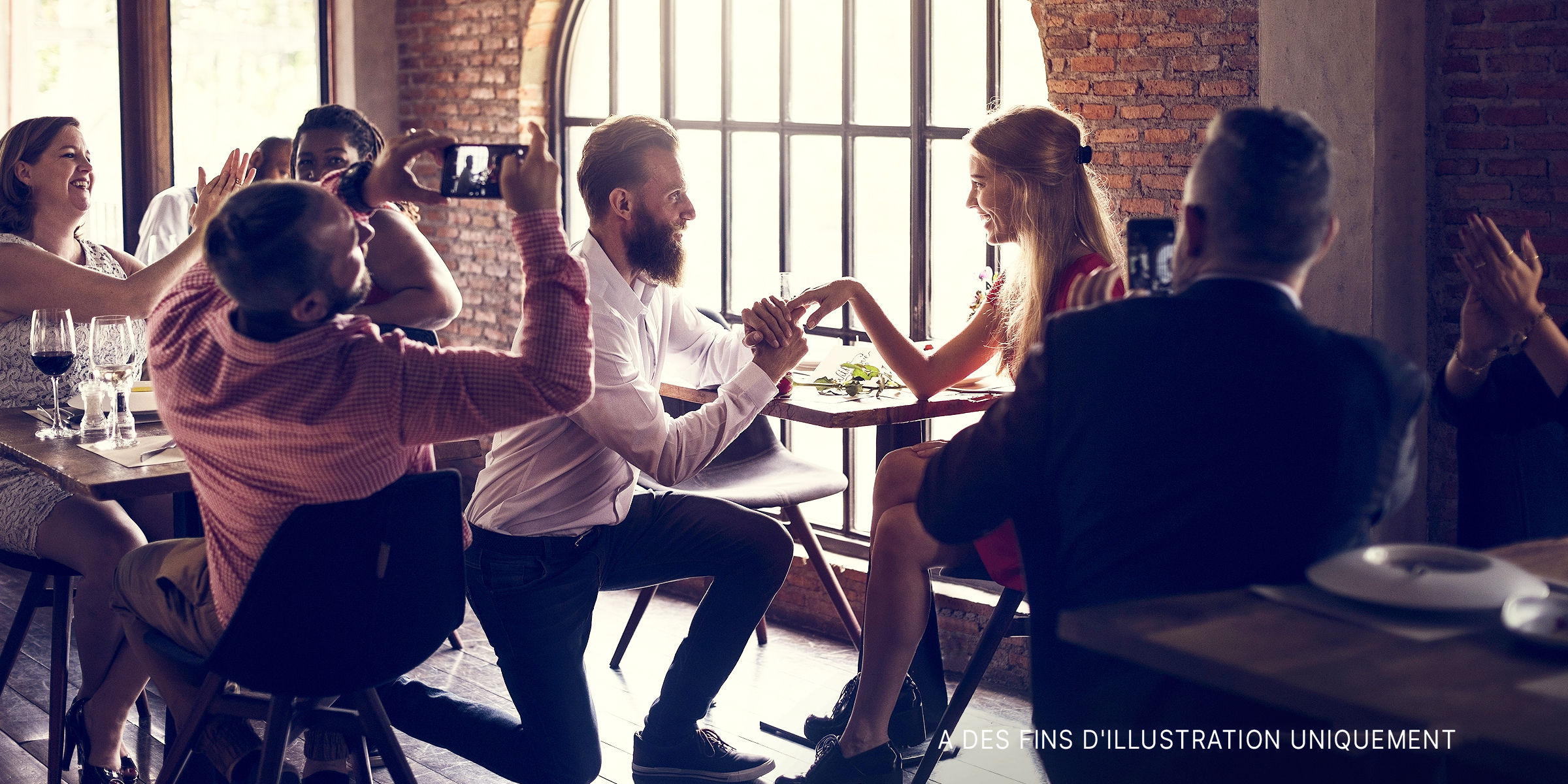 Un homme à genoux, faisant sa demande en mariage dans un restaurant. | Source : Shutterstock