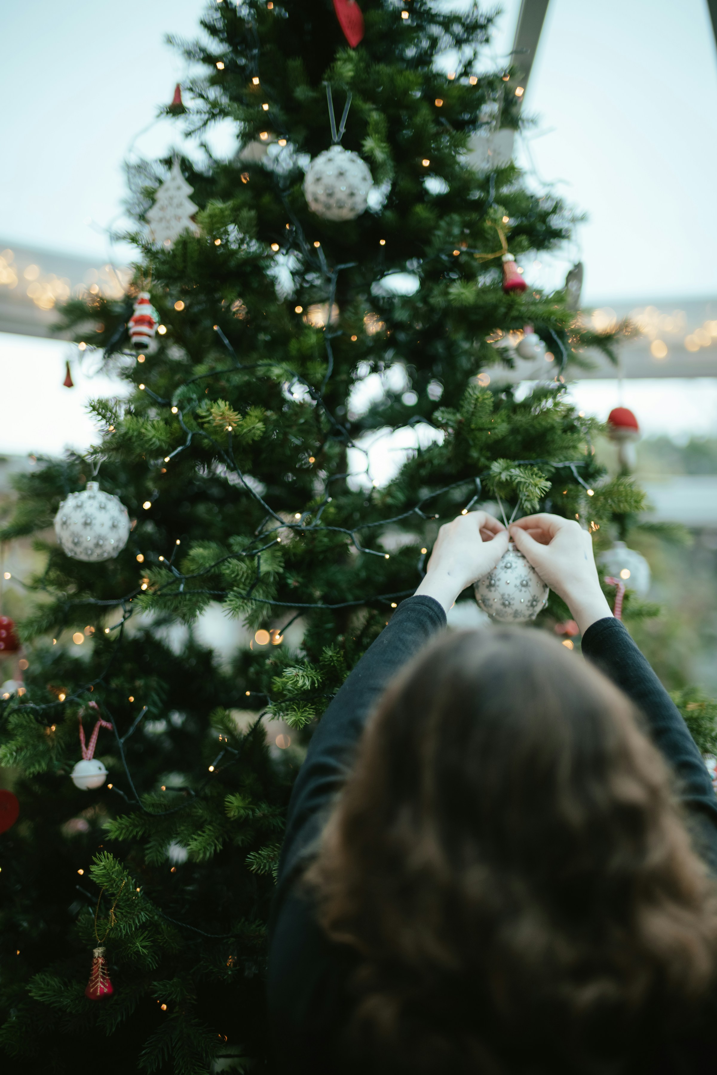 Une femme décorant un arbre de Noël | Source : Unsplash